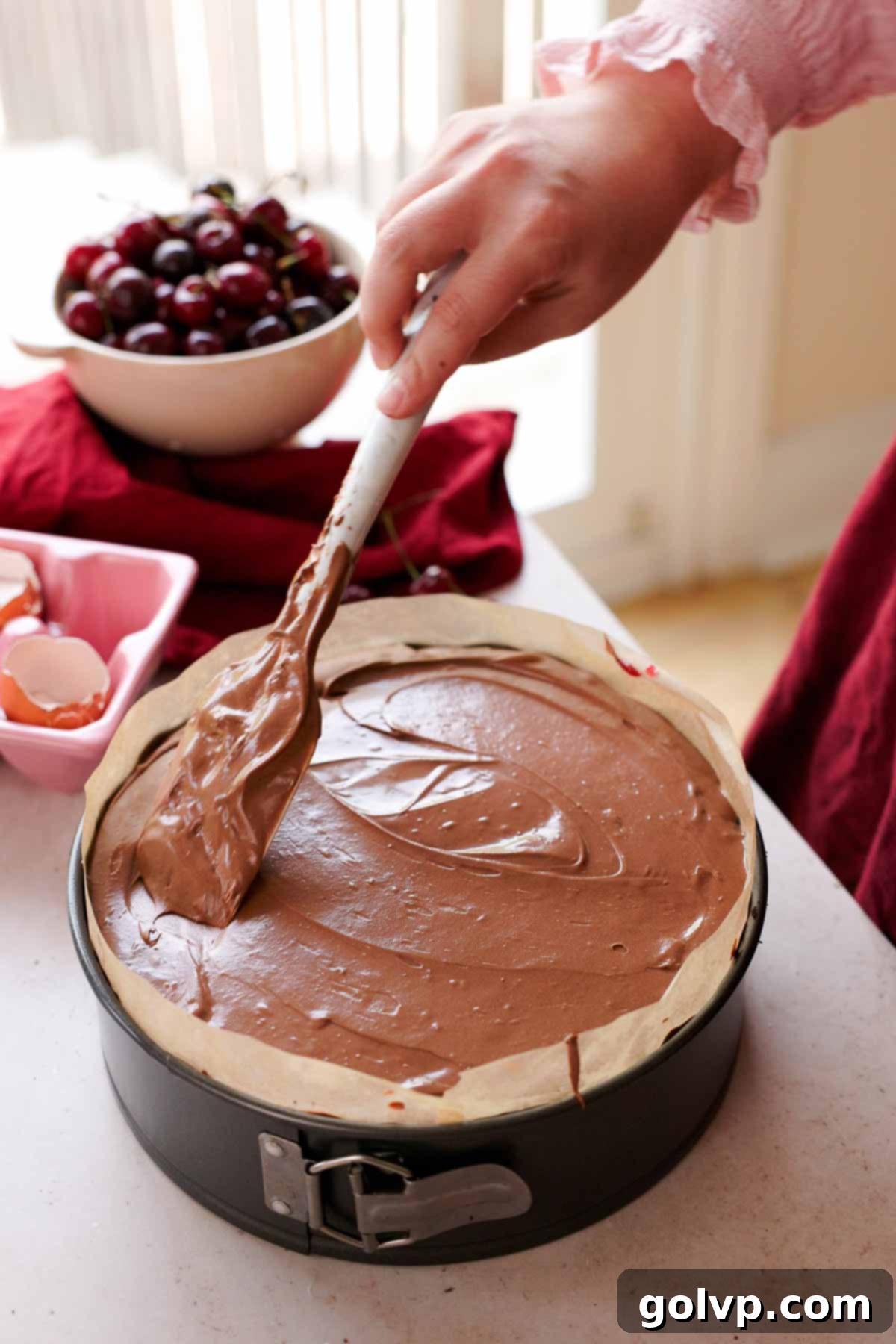 smoothing the top of chocolate cherry cheesecake with a spatula