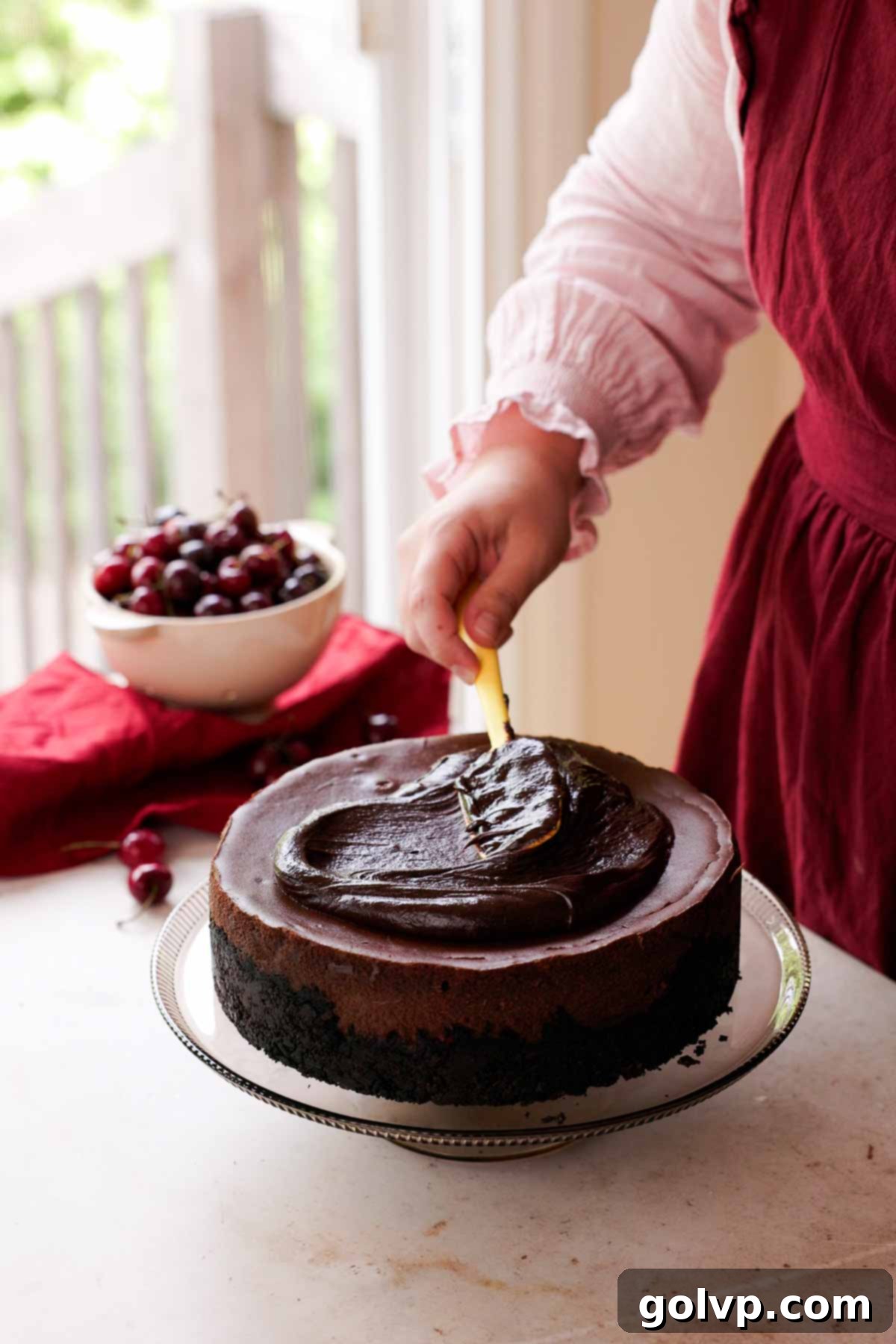 smoothing chocolate ganache onto black forest cheesecake
