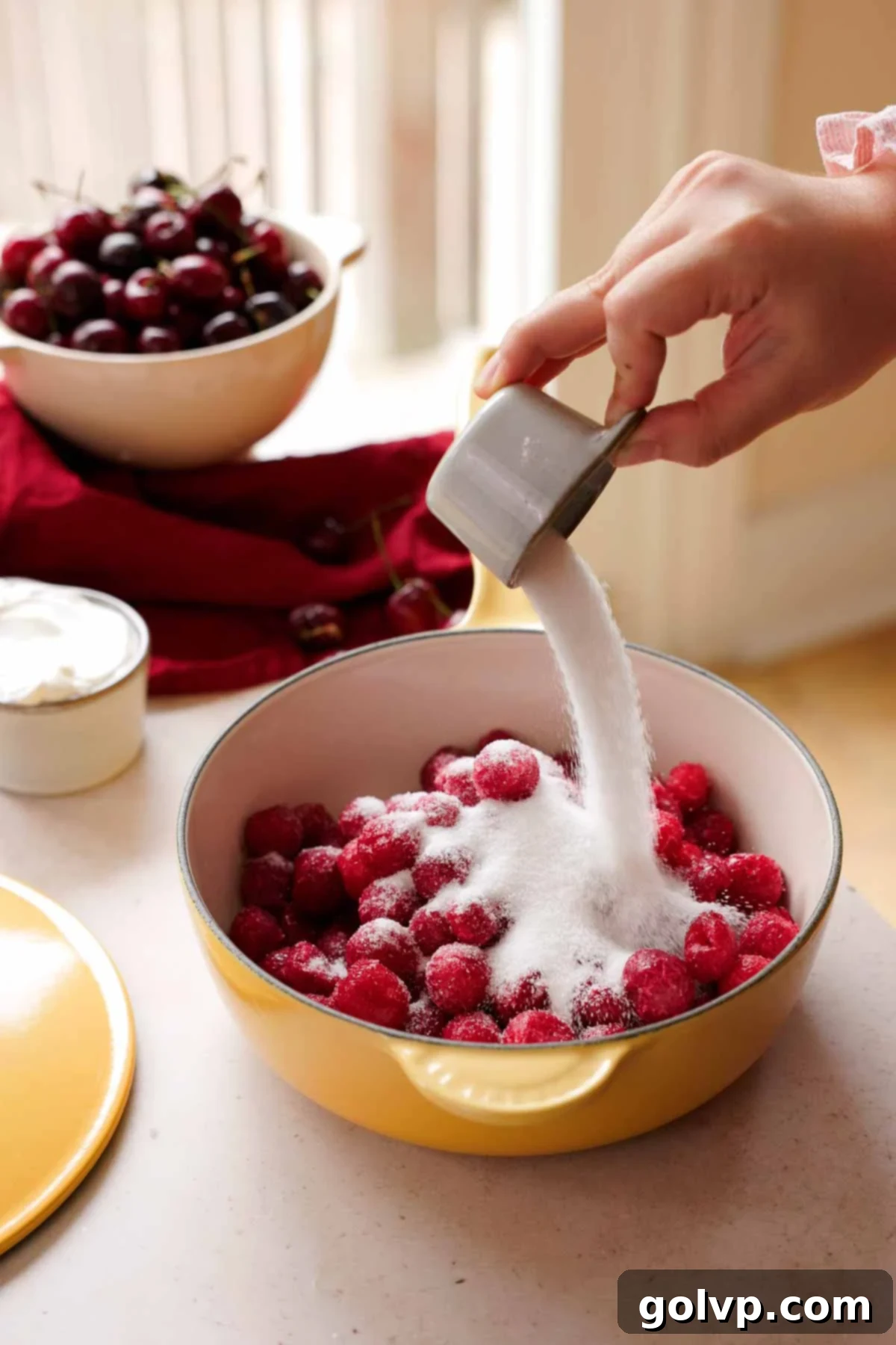 pouring sugar into frozen tart cherries in saucepan