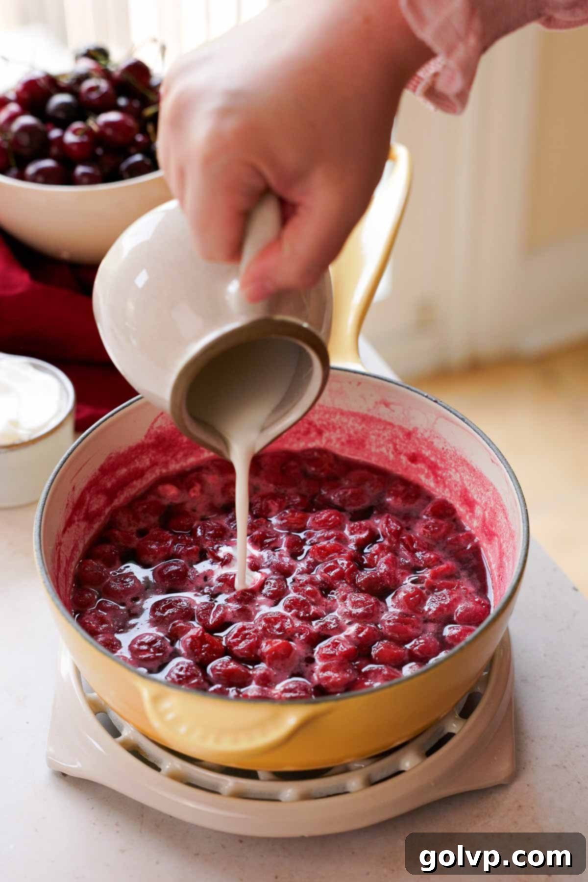 pouring cornstarch slurry into simmering cherries