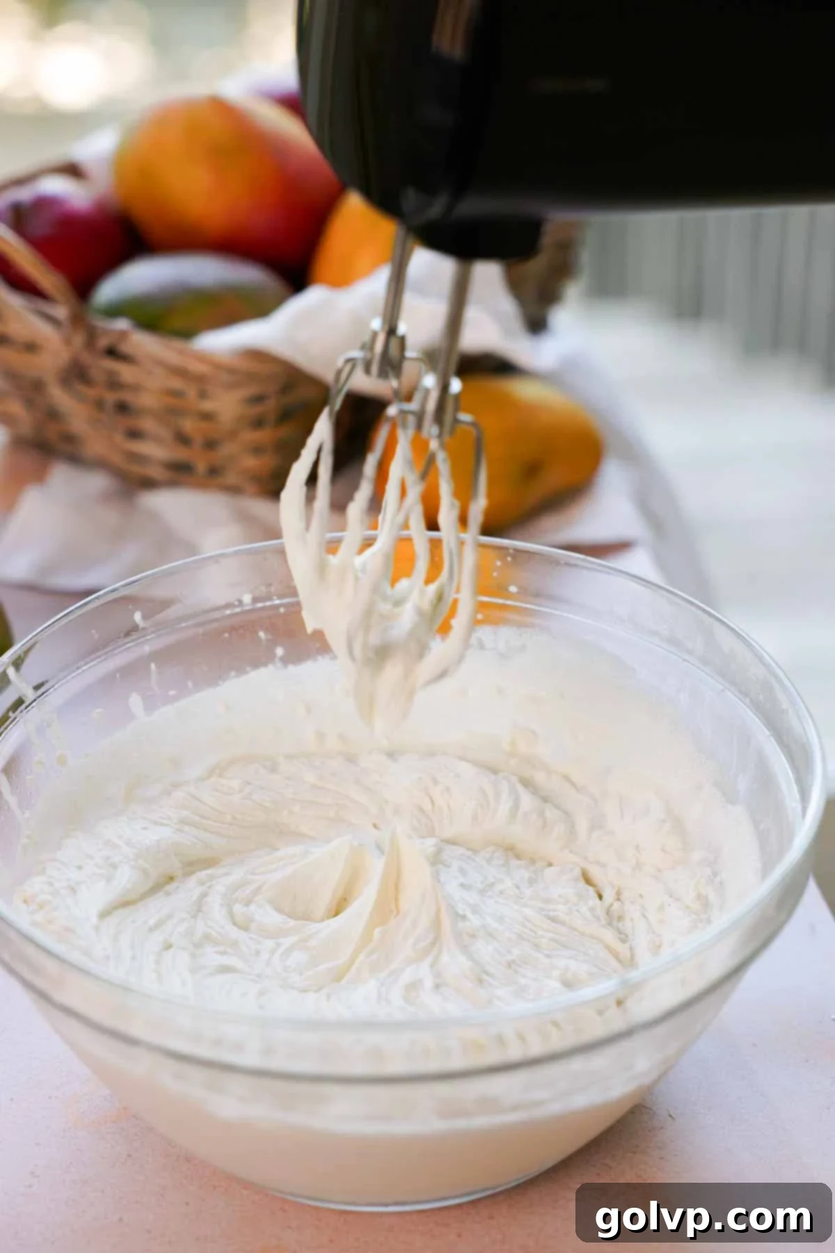 Whipped cream and mascarpone cheese blended together to stiff peaks in a large glass bowl, creating the rich base for the tiramisu filling.