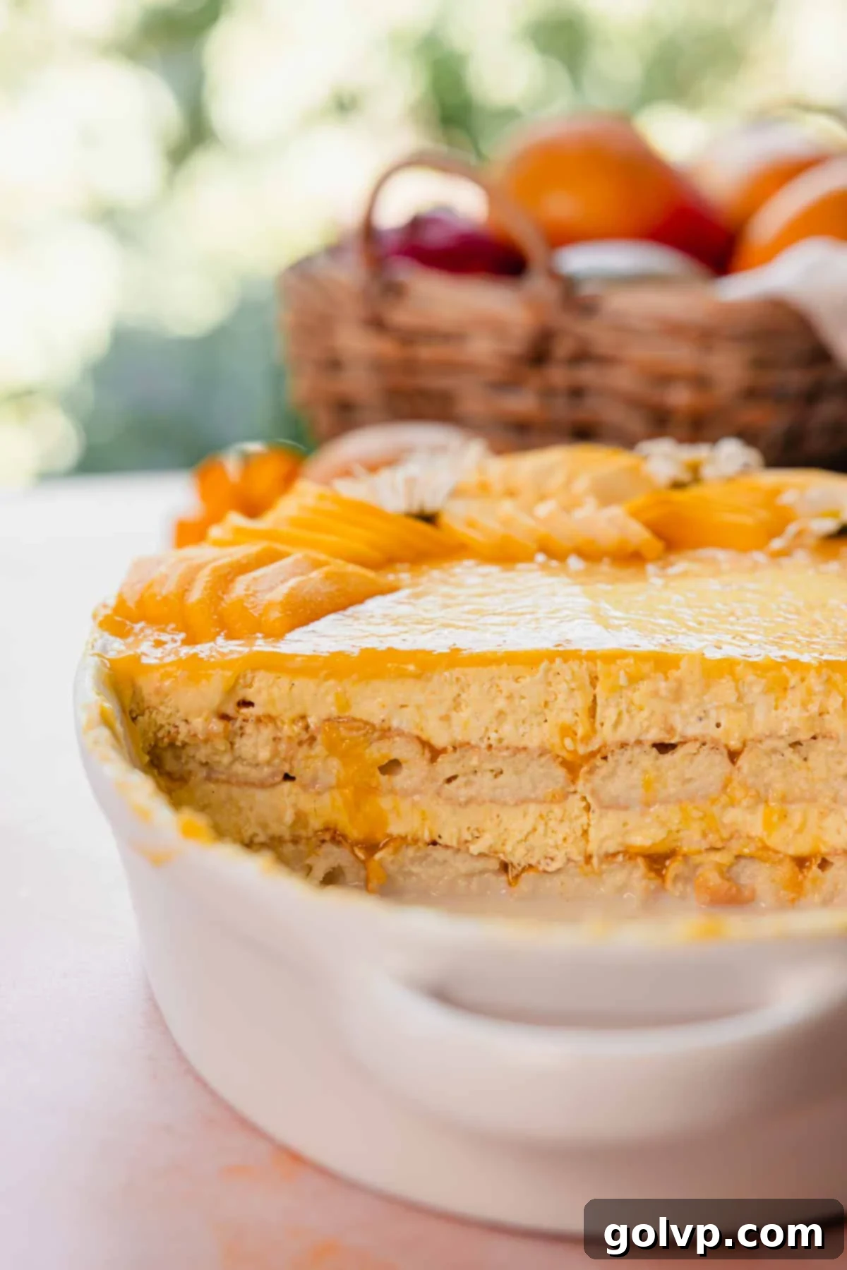 A close-up showing the creamy, smooth texture of mango tiramisu in a white rectangular dish, ready to be scooped or sliced.