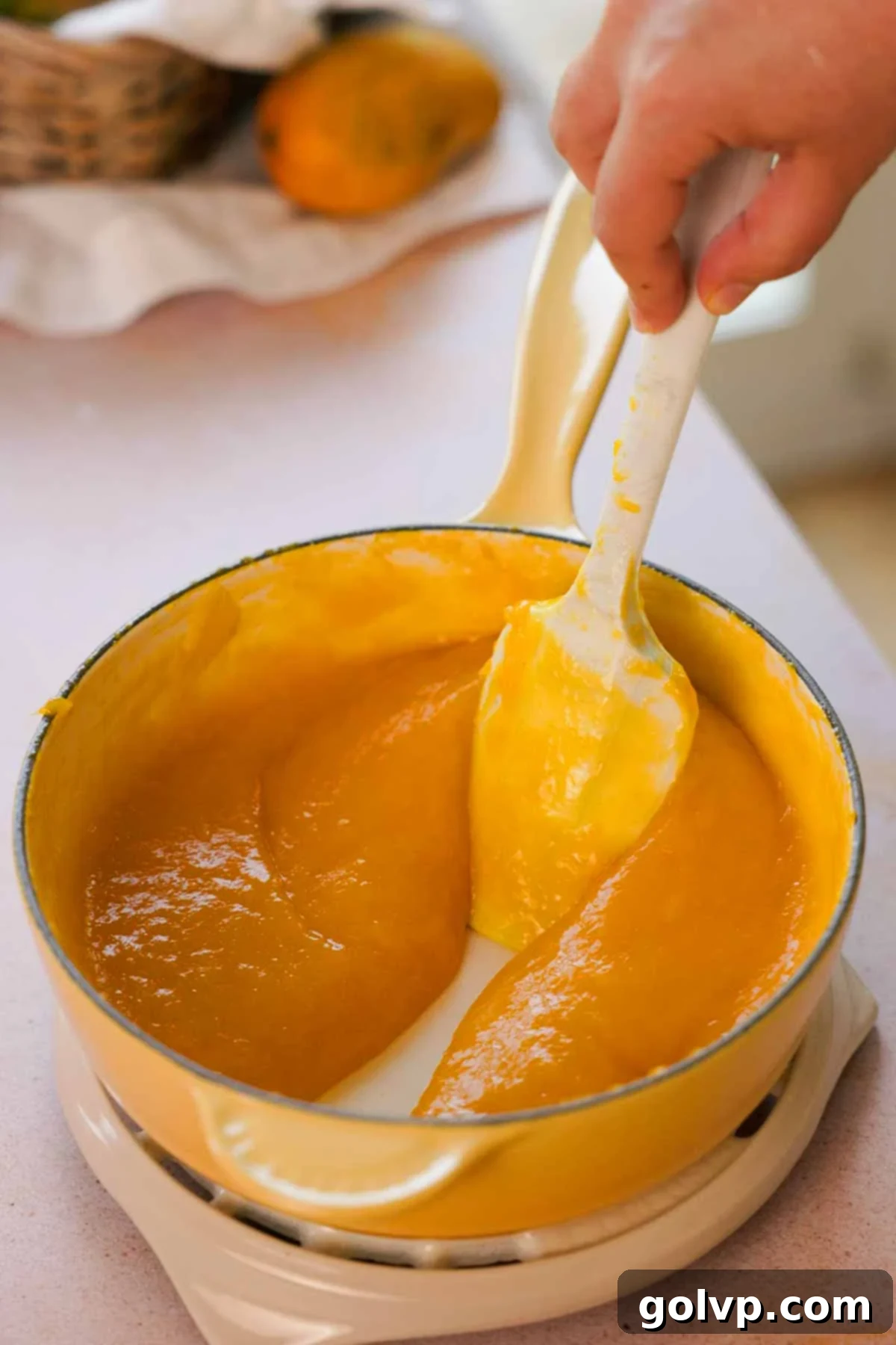 Smooth, vibrant yellow mango puree blended in a saucepan, ready for cooling and further use in the recipe.