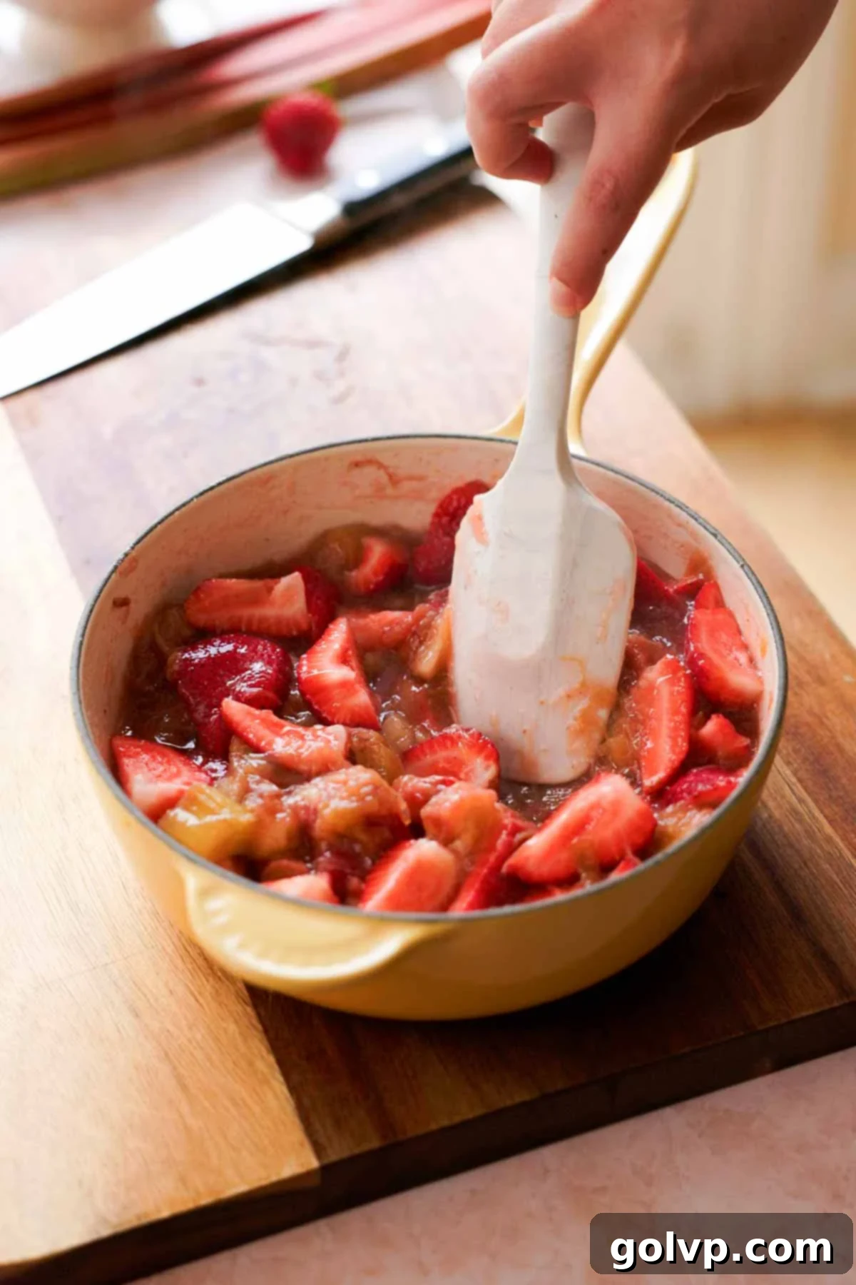 adding fresh strawberries into rhubarb compote