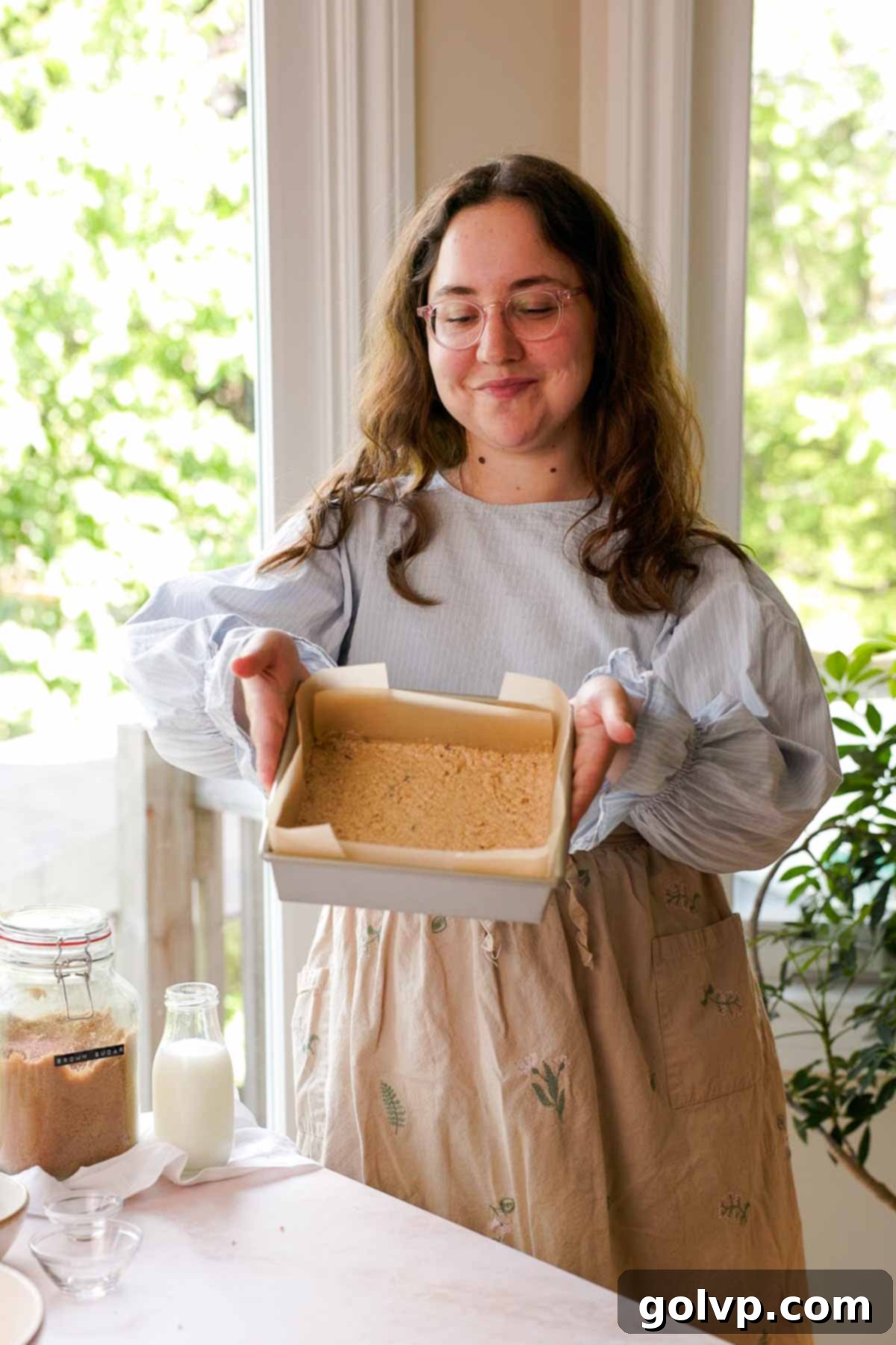 holding spread out oatmeal cookie dough in baking pan