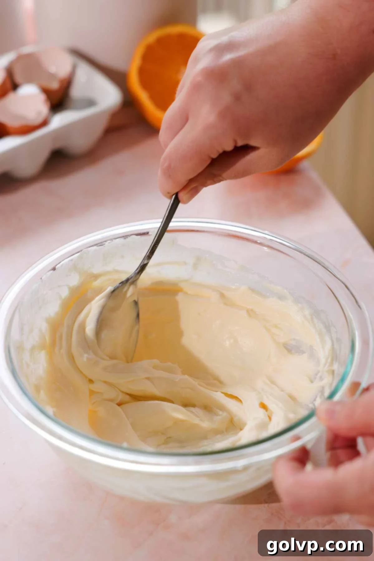 stirring muffin cream cheese filling in bowl with a spoon