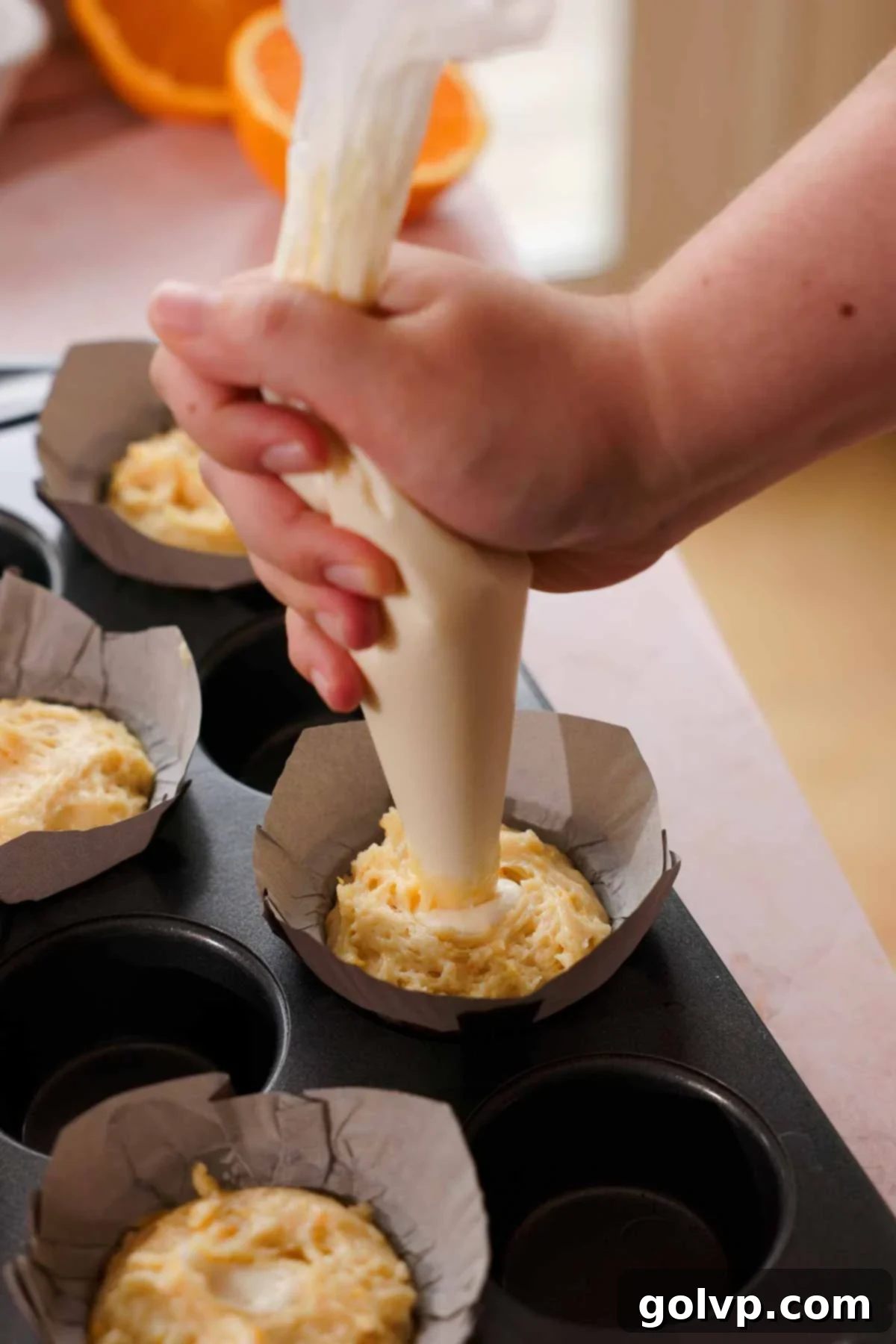piping cream cheese mixture into muffin batter