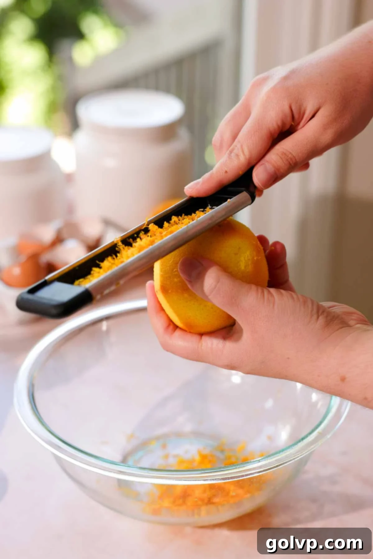 grating orange zest into glass bowl