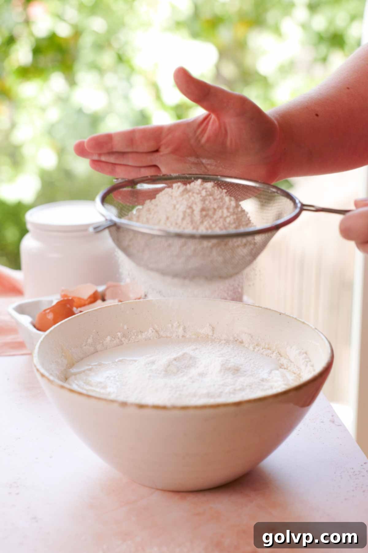 sifting dry ingredients into coconut batter