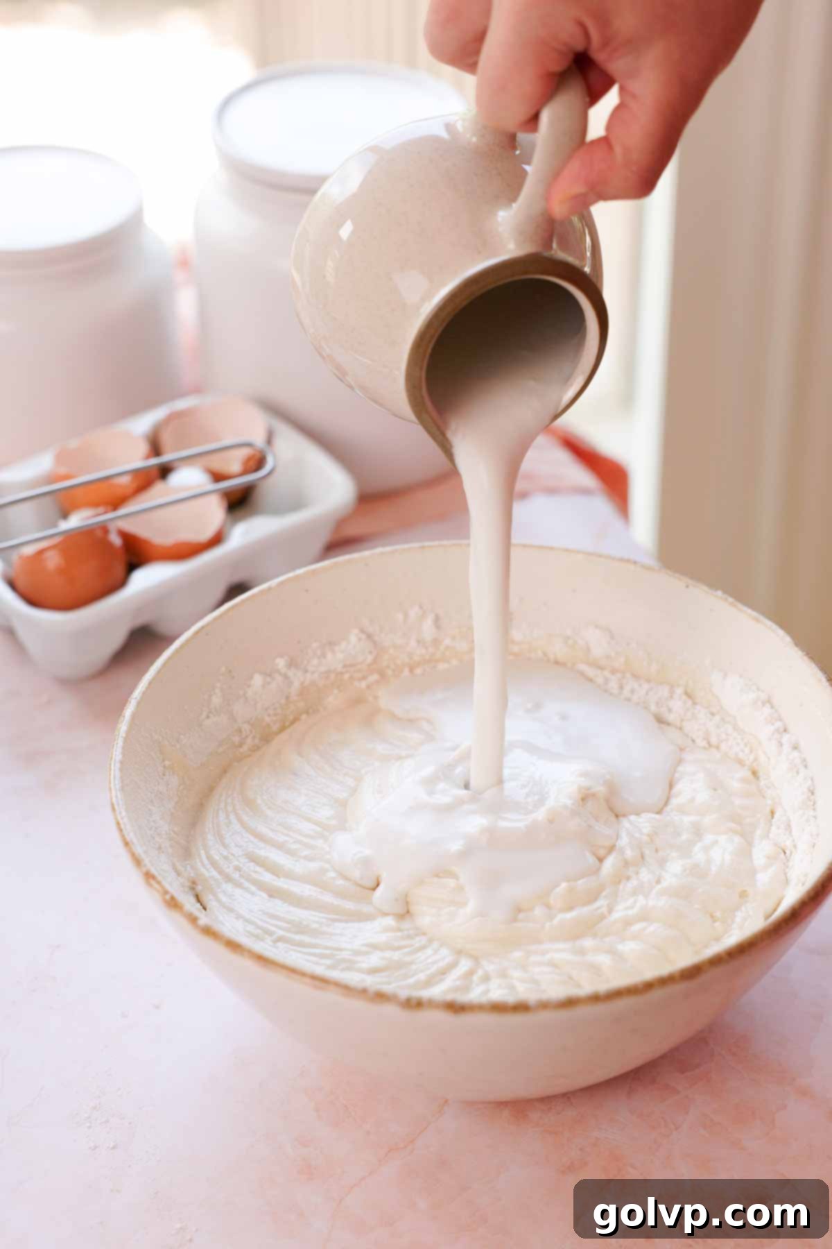 pouring coconut milk into coconut cake batter