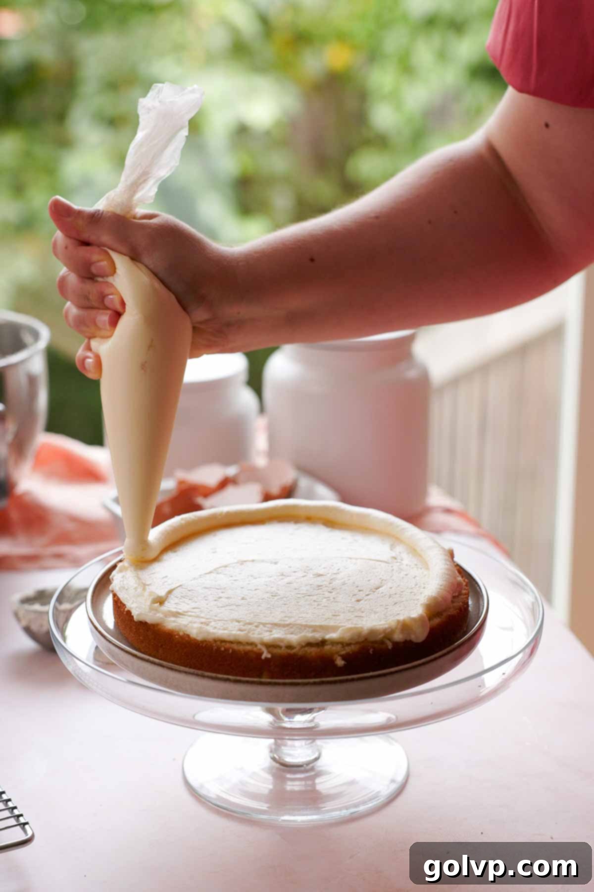 piping frosting border on coconut cake layers