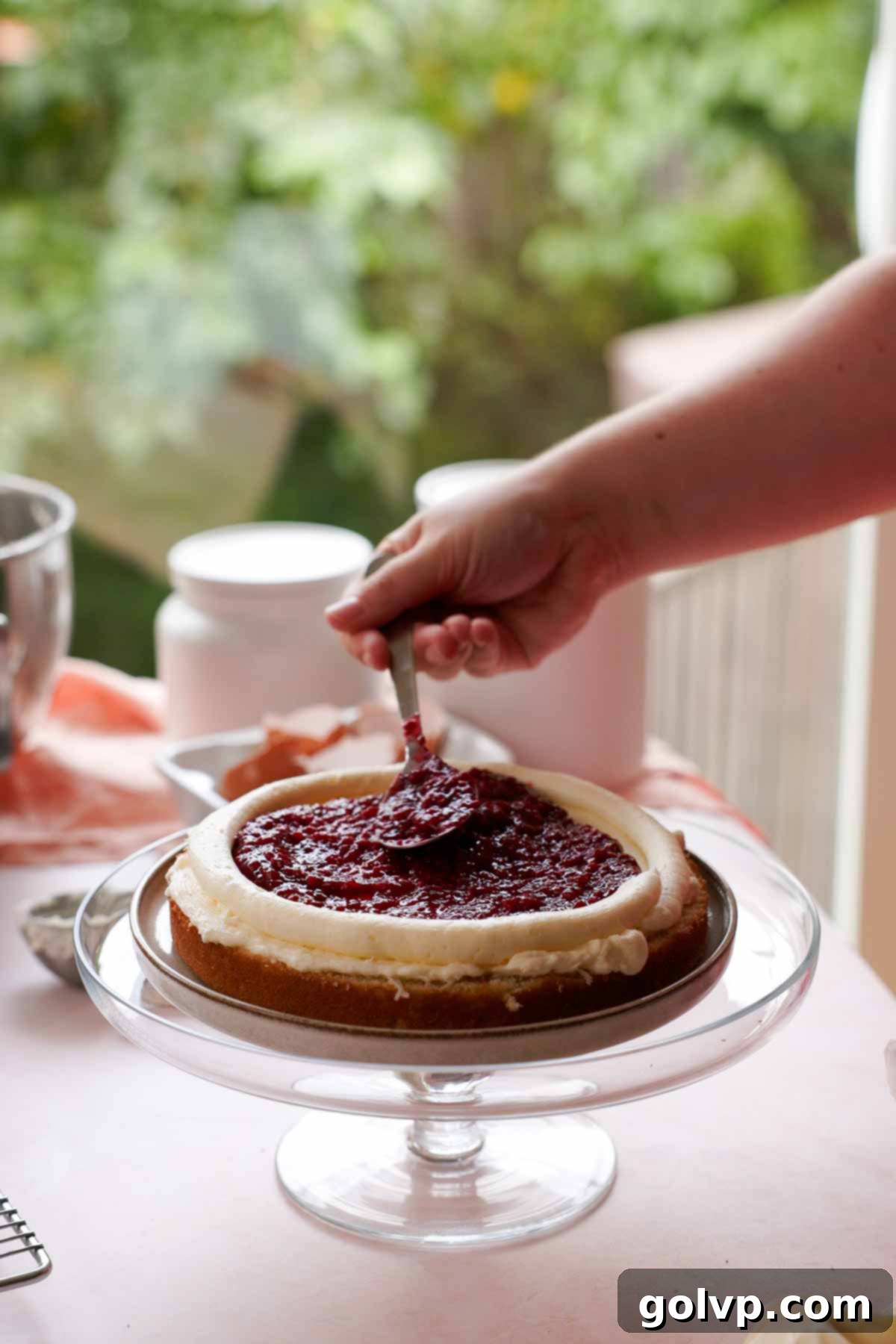 layering raspberry filling in between cake layers with a spoon