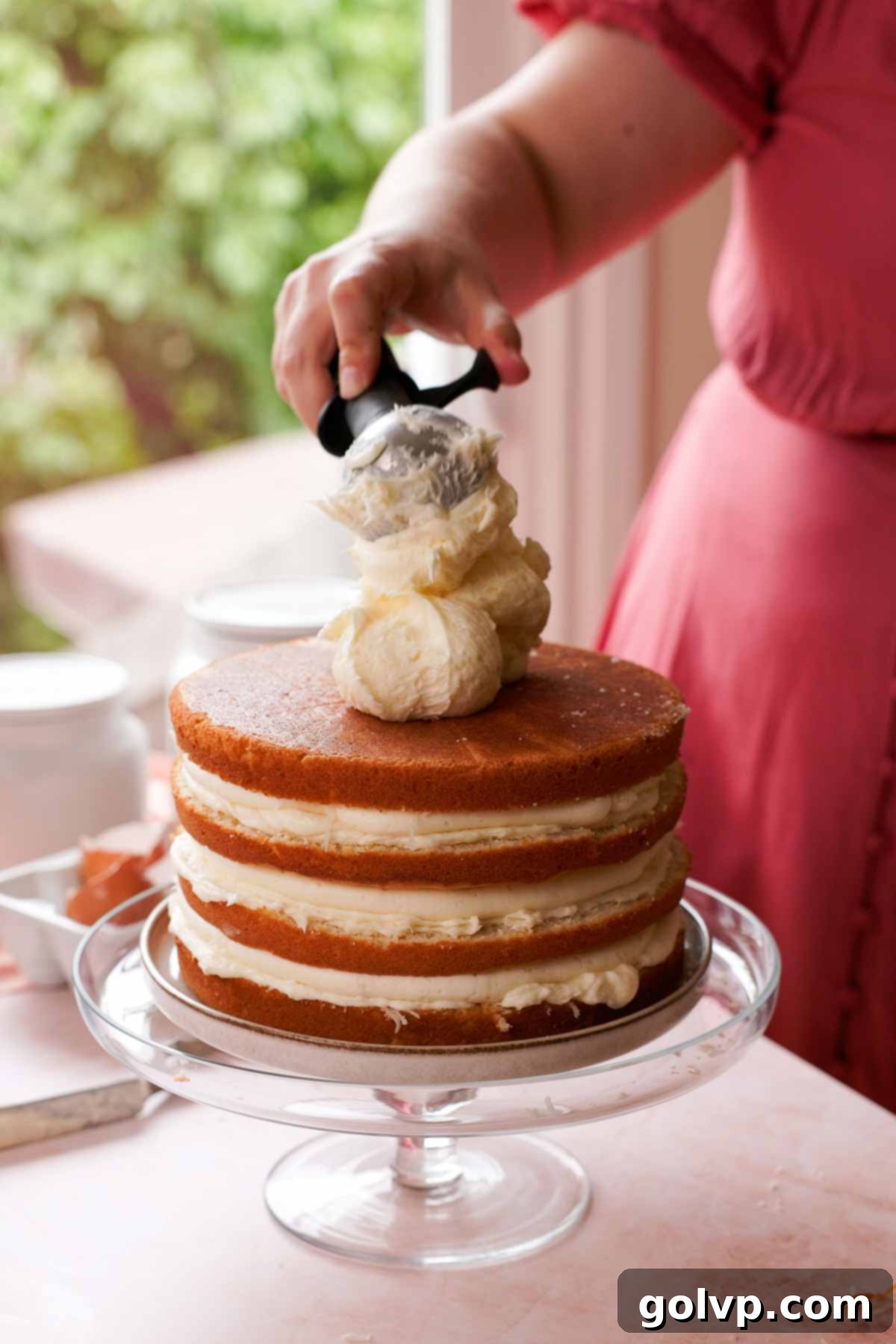 scooping coconut cream cheese frosting onto coconut cake