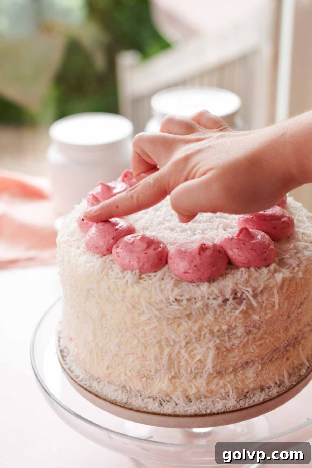 patting raspberry frosting peaks with fingers