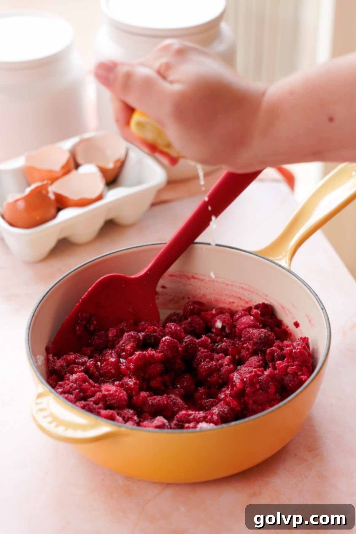 squeezing lemons into frozen raspberry cake filling