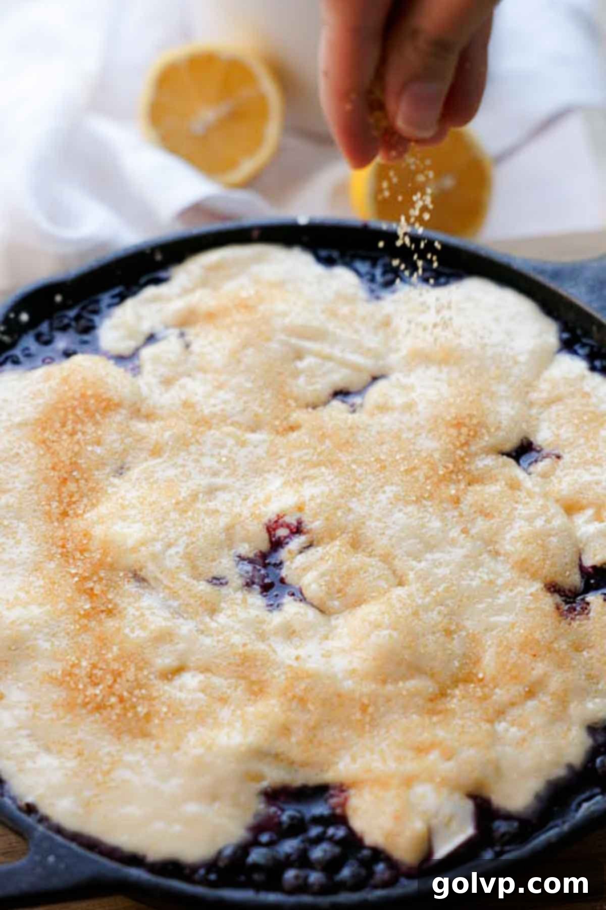 sprinkling demerara sugar onto blueberry cobbler