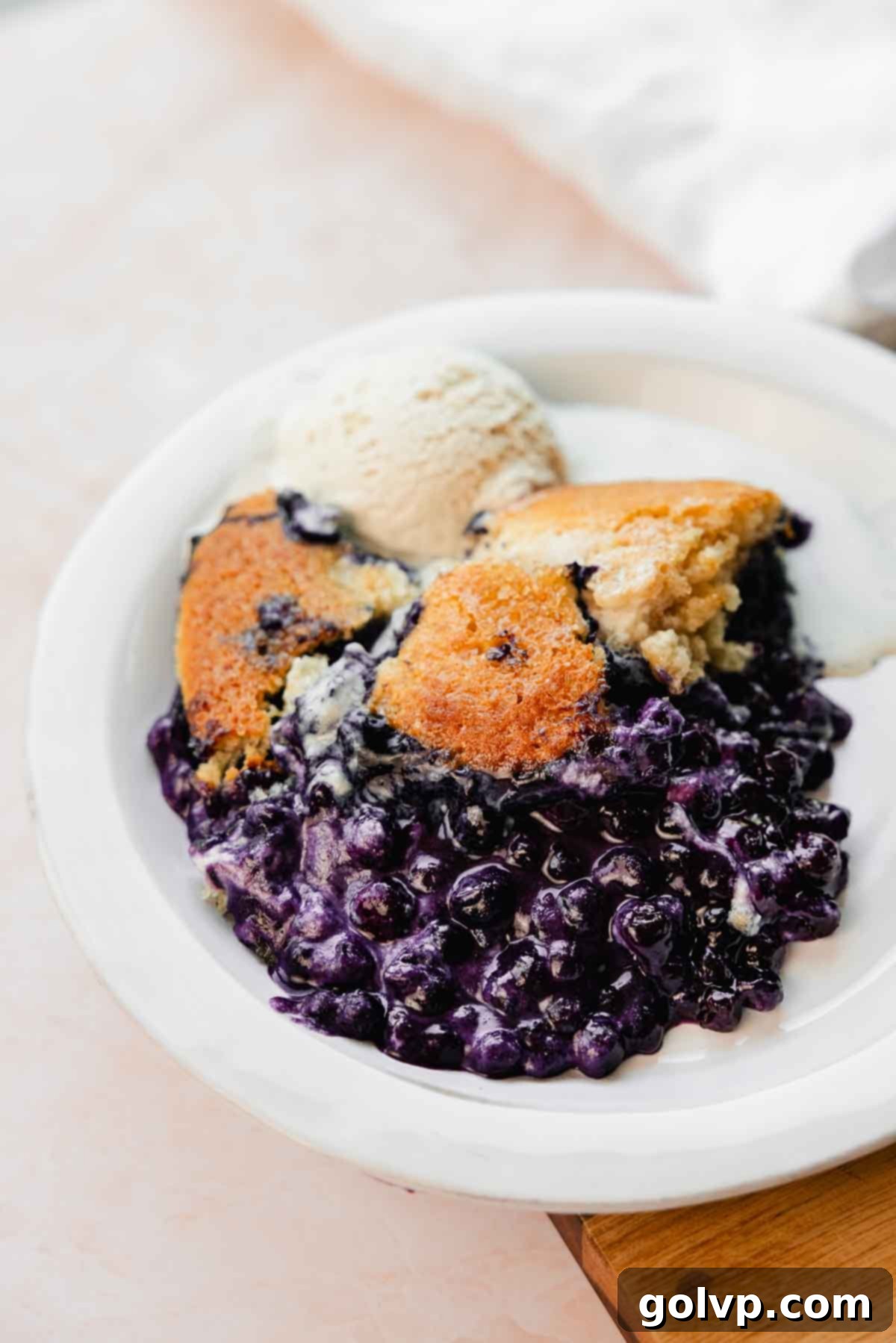 blueberry cobbler on plate with ice cream scoop