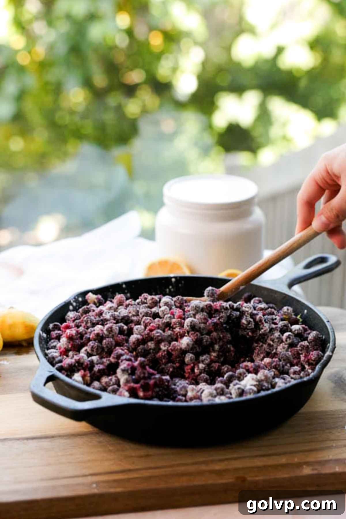 stirring blueberry cobbler filling in cast iron pan