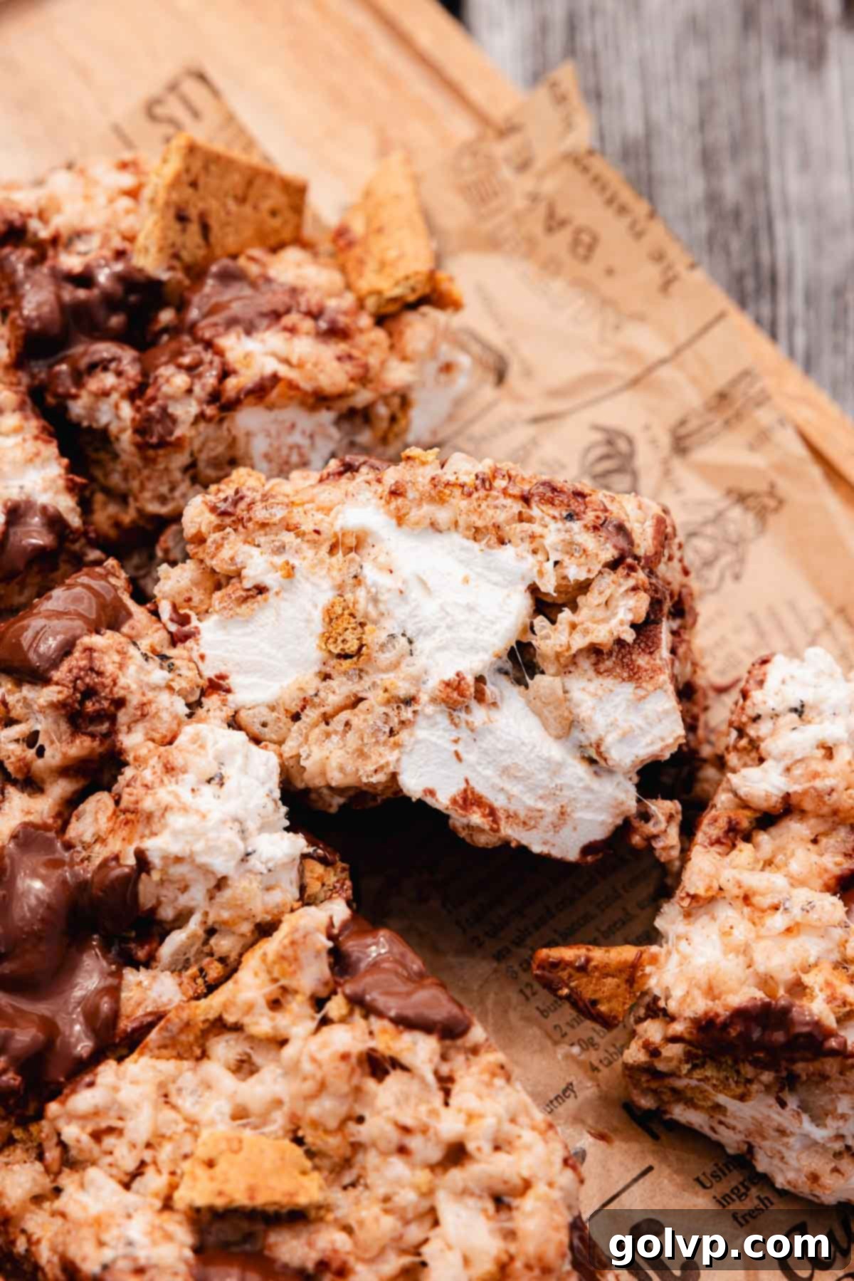 Closeup of S'mores Rice Krispies Treats bars in a pan, featuring prominent chunks of toasted marshmallow and graham crackers.