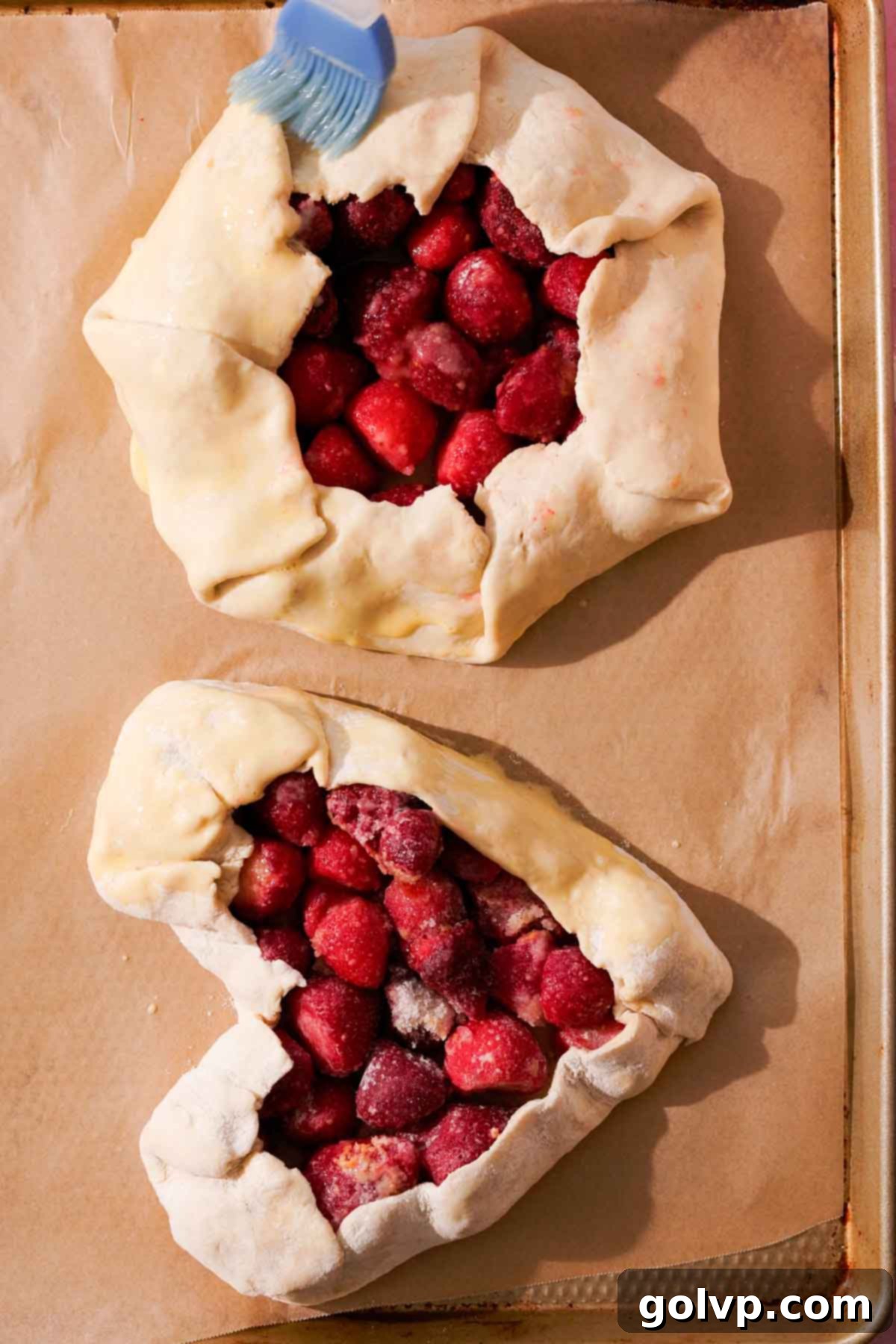 Two shaped galettes on a baking sheet, one round and one heart-shaped, ready for baking.