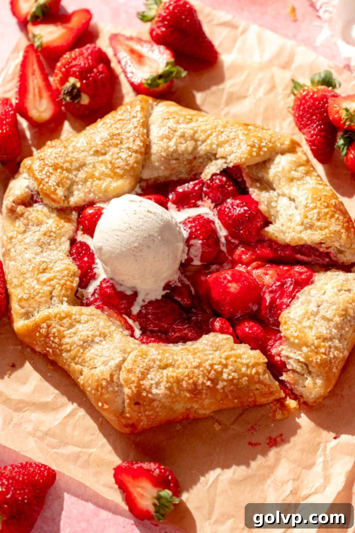 A warm strawberry galette with a scoop of melting vanilla ice cream on top, ready to be served.