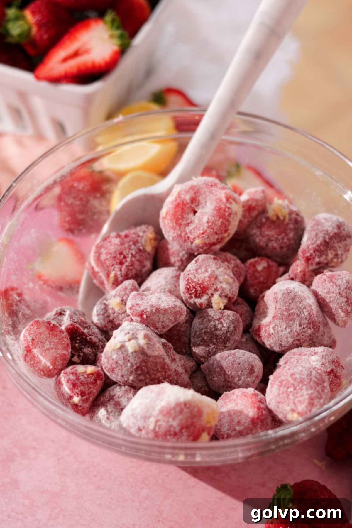 Stirring strawberry galette filling ingredients with a rubber spatula in a clear glass bowl.
