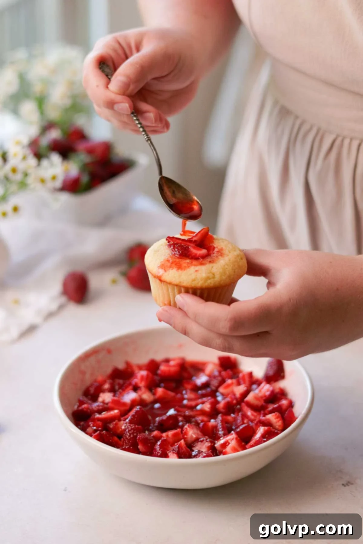 filling the cupcakes with fresh macerated strawberries and pouring the syrup on top