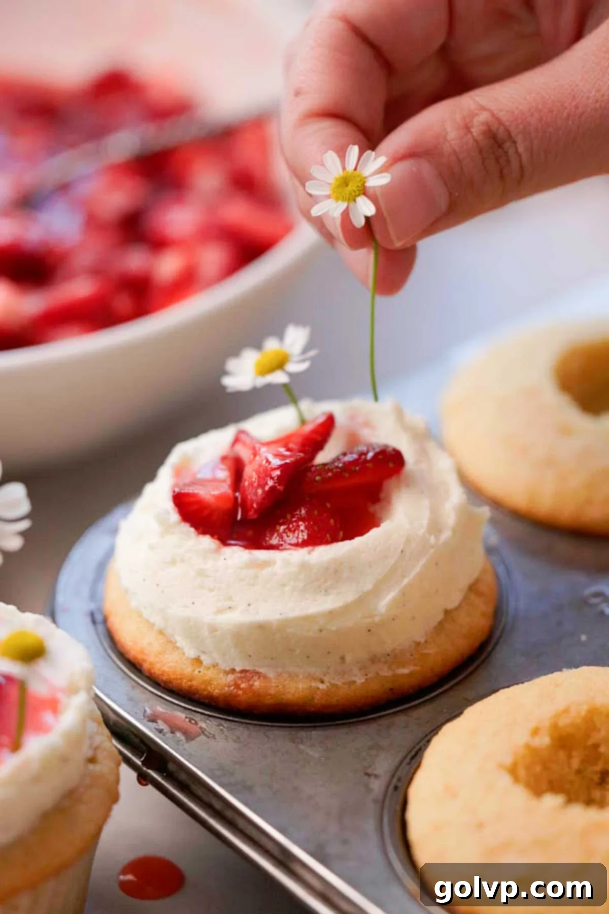decorating the cupcakes with daisies and fresh cut strawberries