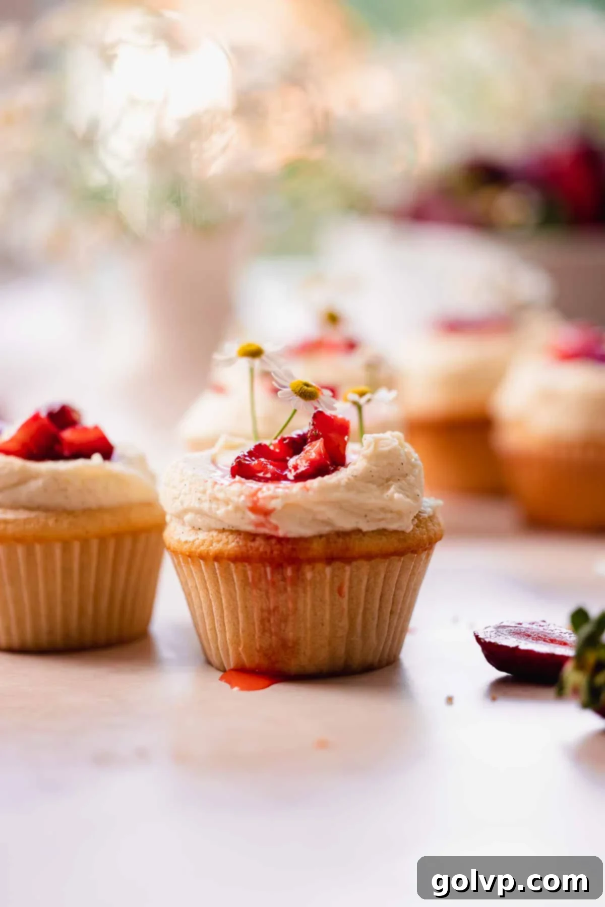 a close up of a white chocolate strawberry cupcake with some strawberry syrup dripping from the top