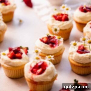 Fresh strawberry and white chocolate cupcakes artfully arranged on a rustic table setting.