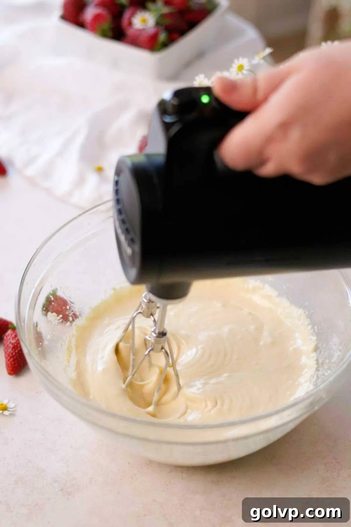vanilla cupcake batter wet ingredients being mixed in a glass bowl with an electric mixer