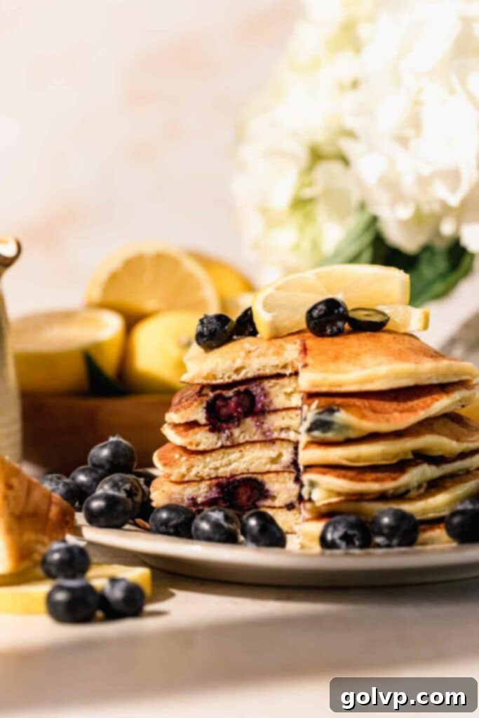 A stack of blueberry lemon ricotta pancakes cut open to reveal their moist, fluffy interior and juicy blueberries, perfect for a close-up food shot.