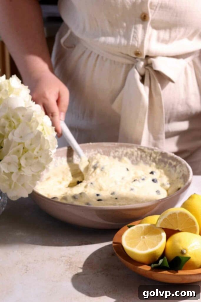 The mixed blueberry lemon ricotta pancake batter with visible lumps, ready for the blueberries to be folded in, illustrating the ideal texture for fluffy pancakes.