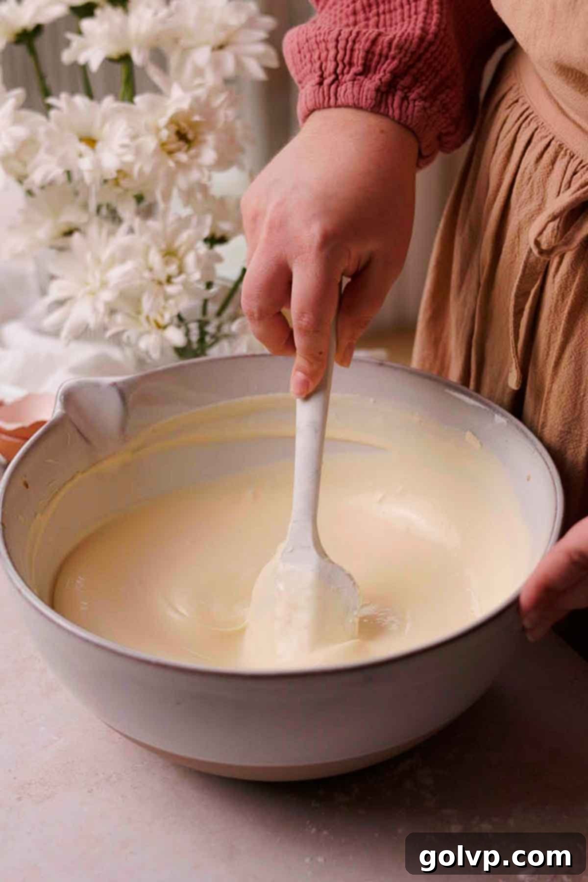 stirring cheesecake batter with spatula in large bowl