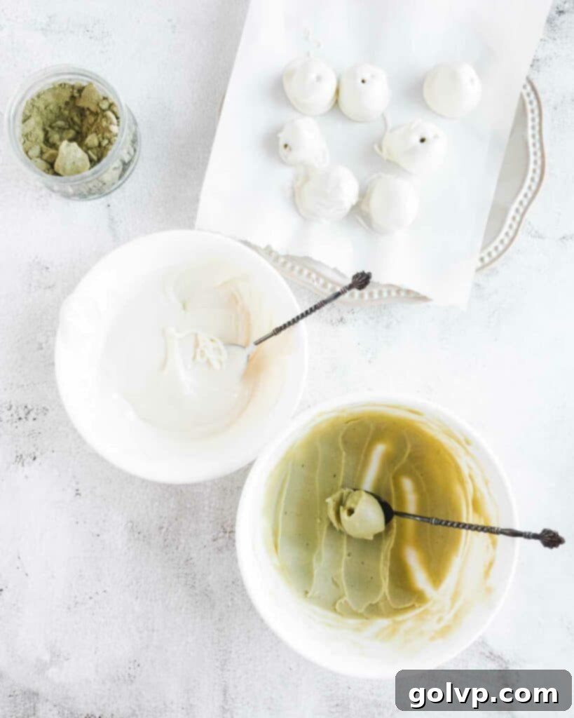 Hands carefully scooping and dipping matcha truffles into melted white chocolate coating.