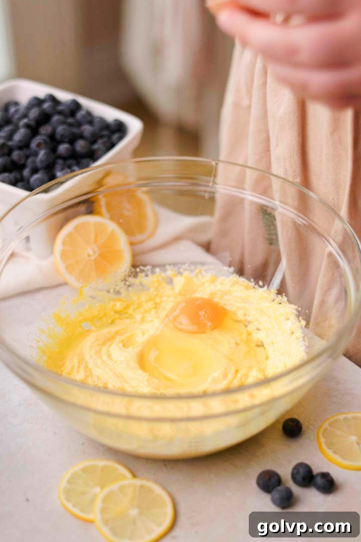 Eggs being added one by one to the creamy cupcake batter in a mixer.