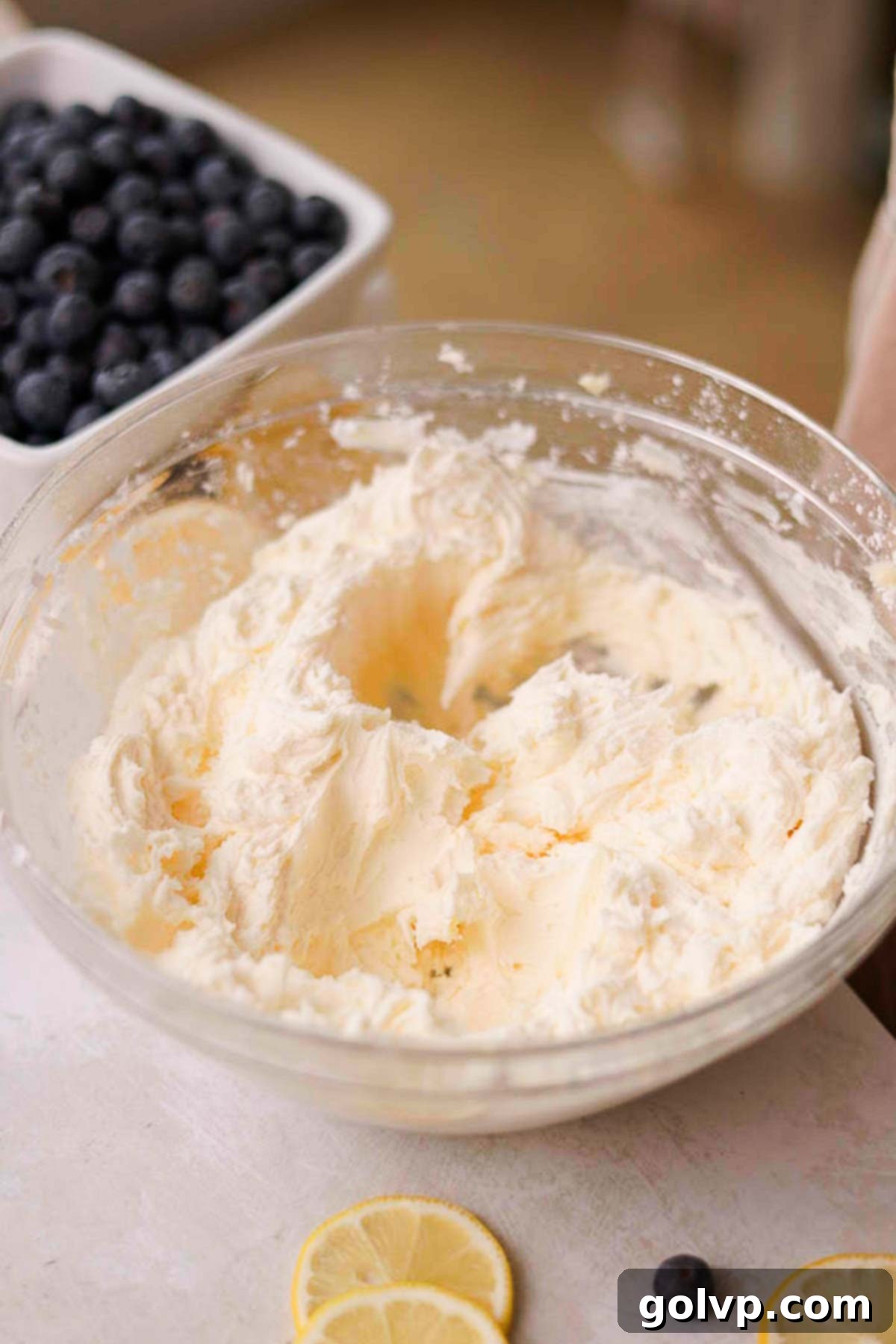 Whipped butter and powdered sugar for blueberry cream cheese frosting in a mixing bowl.