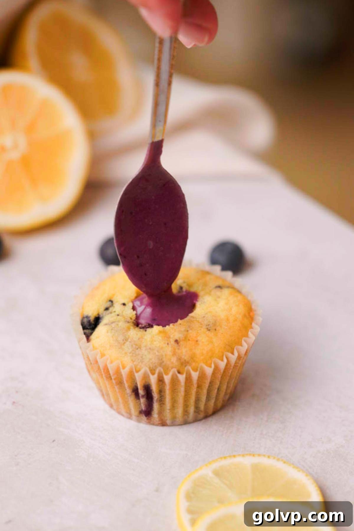 A blueberry cupcake being filled with blueberry curd after coring.