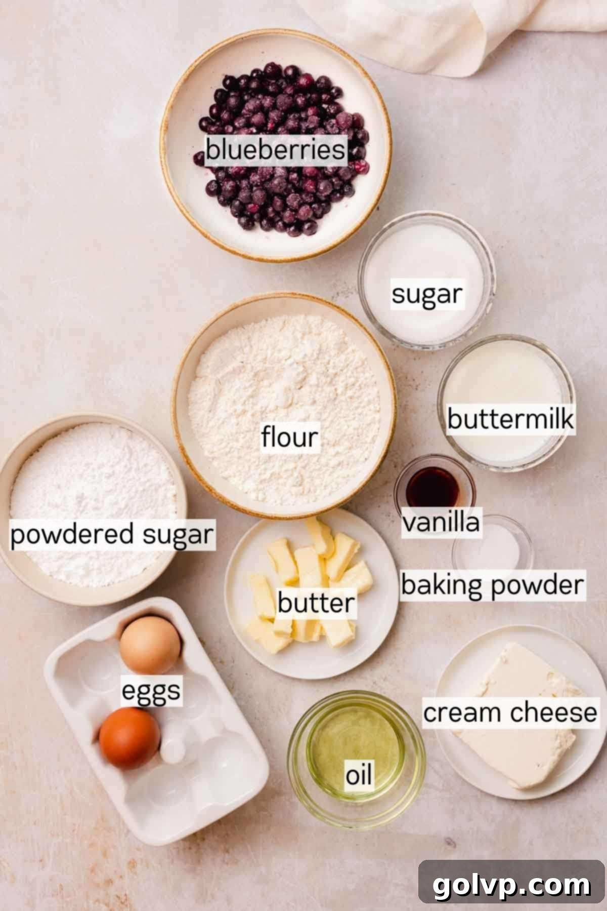 Bowls of ingredients for blueberry cupcakes including flour, sugar, butter, and blueberries.