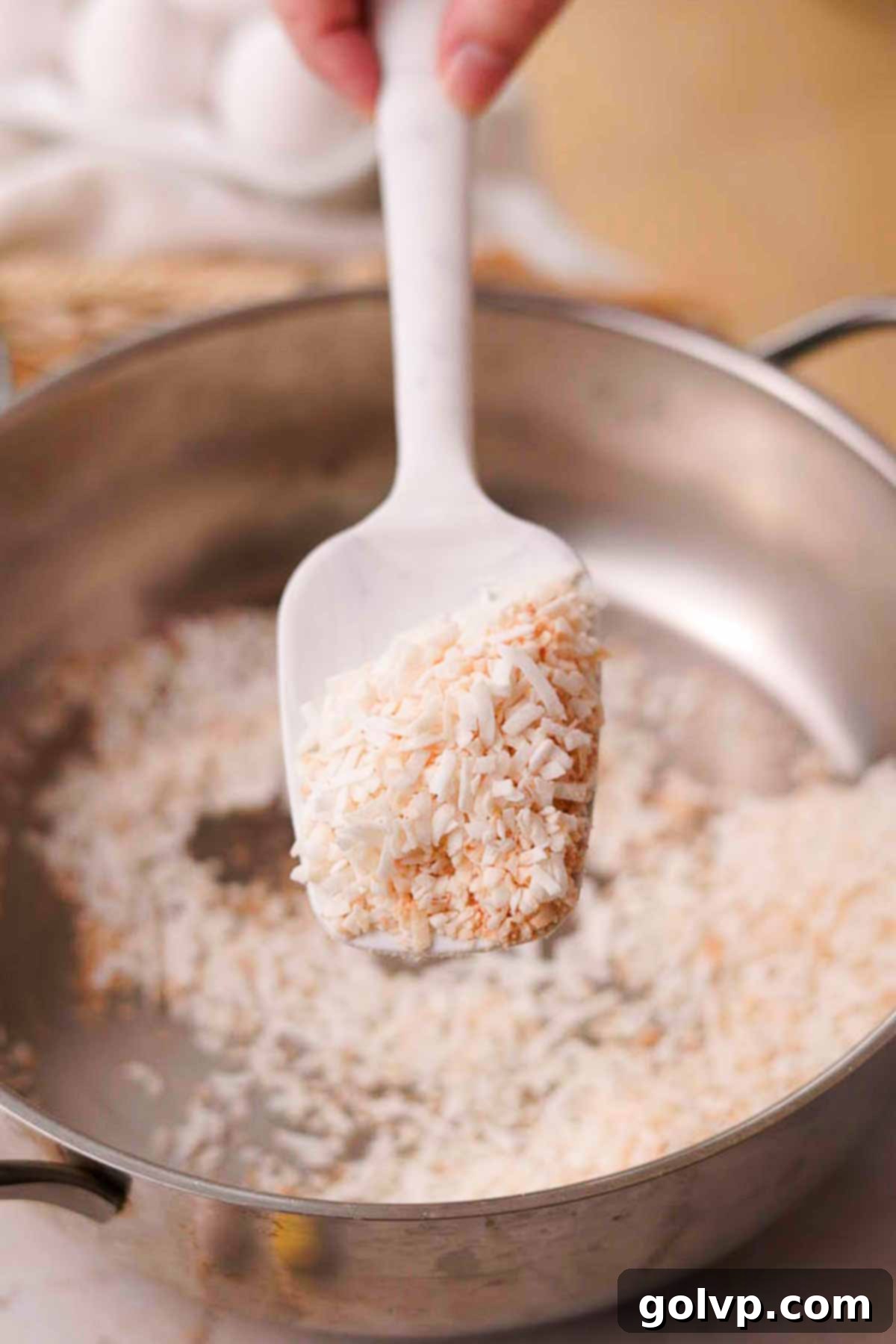 Toasting shredded coconut in a dry pan until lightly golden brown