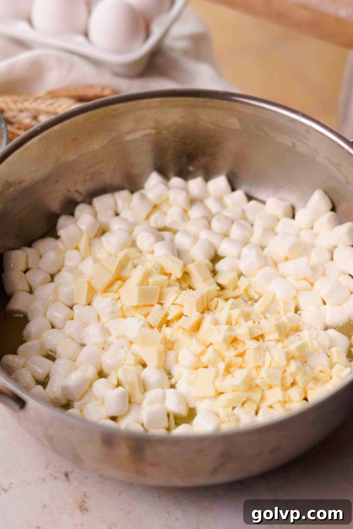 Combining butter, mini marshmallows, and chopped white chocolate in a saucepan