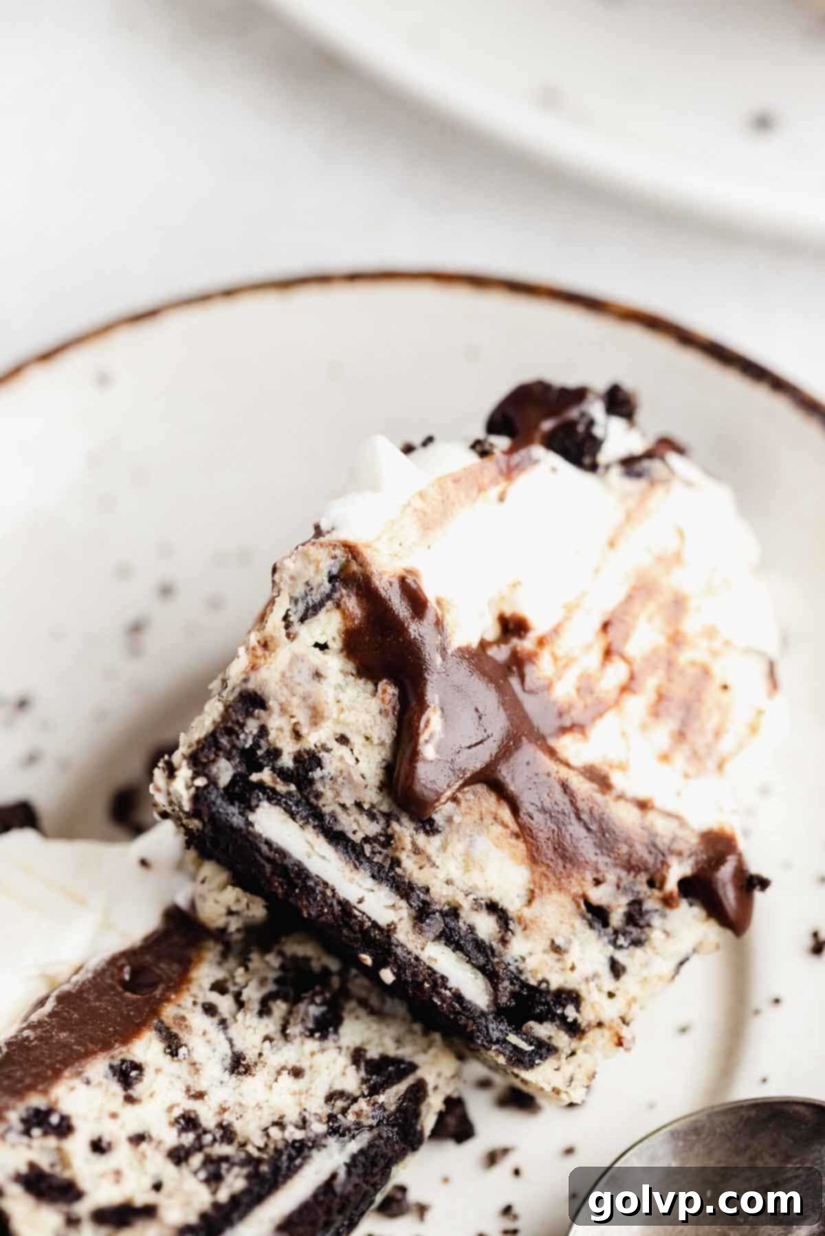 Closeup of a cut-open mini Oreo cheesecake showcasing the whole Oreo base, creamy filling, and layered toppings.