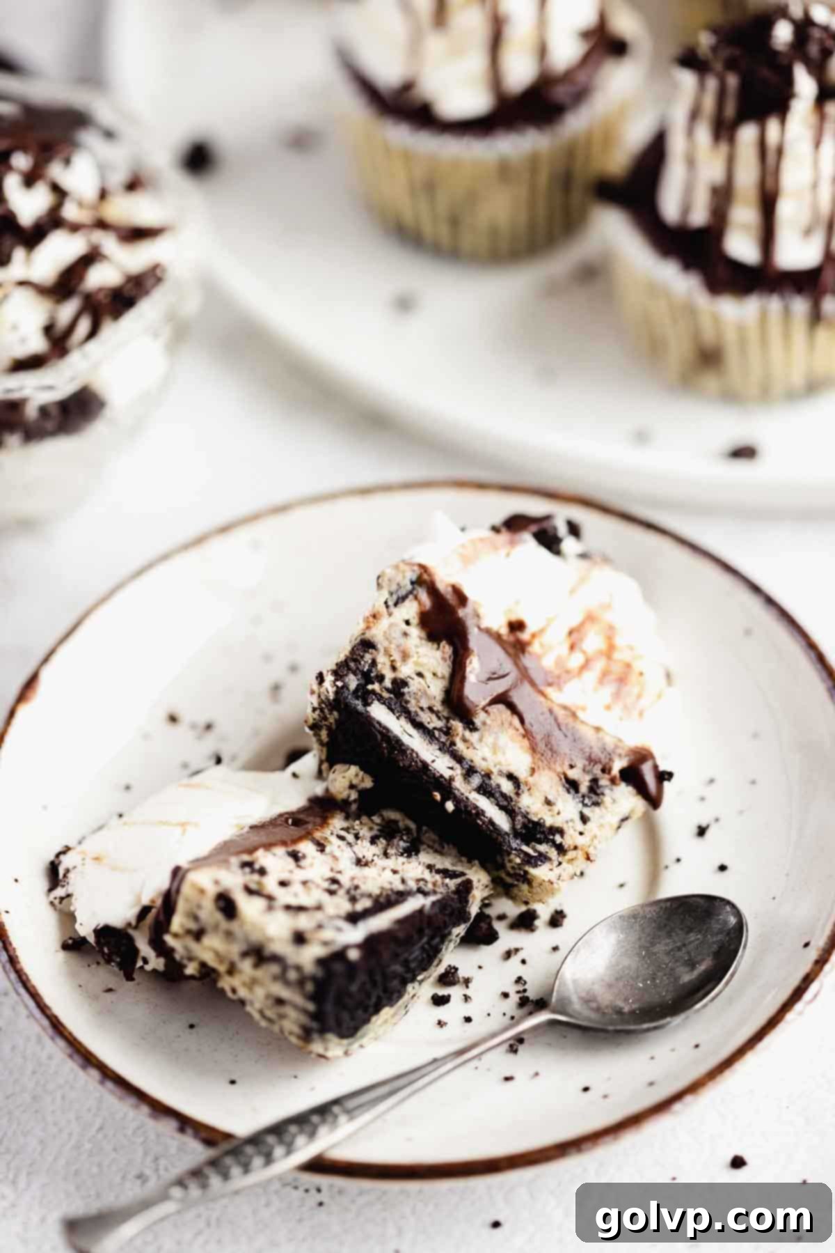 Cut cheesecake on a plate with a spoon, showing the whole Oreo base.