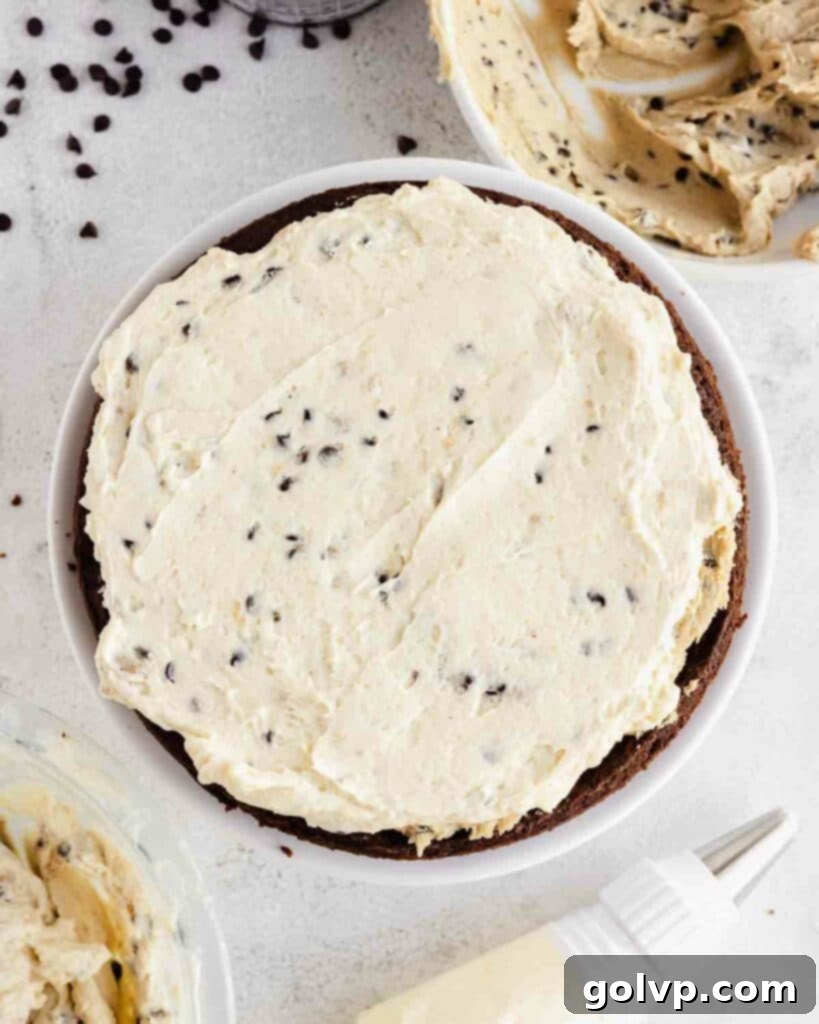 spreading cookie dough frosting on cake, creating an even layer