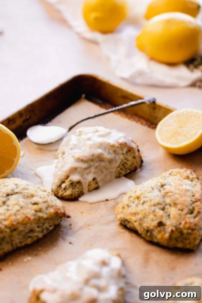 Lemon poppy seed scones with vibrant lemon glaze drizzled on top, arranged beautifully on parchment paper