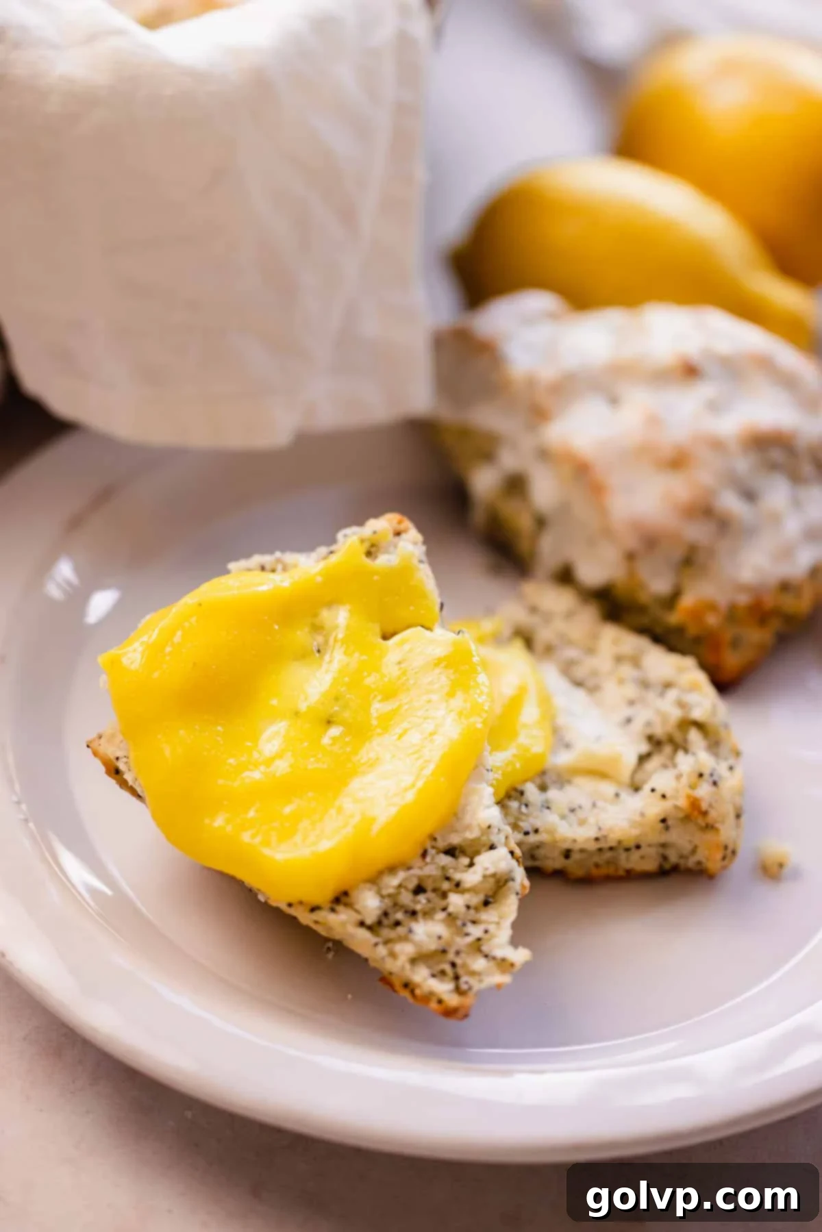 Closeup of a lemon poppy seed scone with a smear of yellow lemon curd