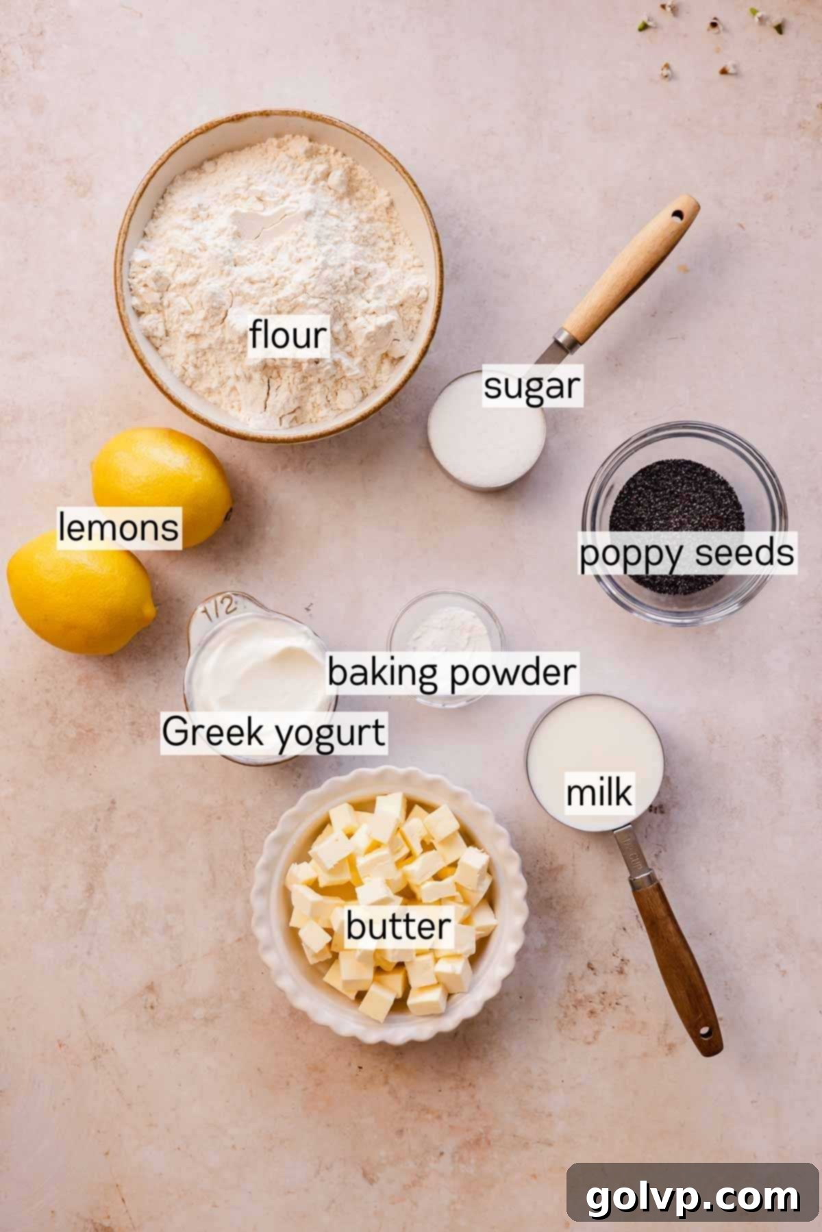 Various ingredients for lemon poppy seed scones, including lemons, poppy seeds, butter, and flour, arranged in bowls