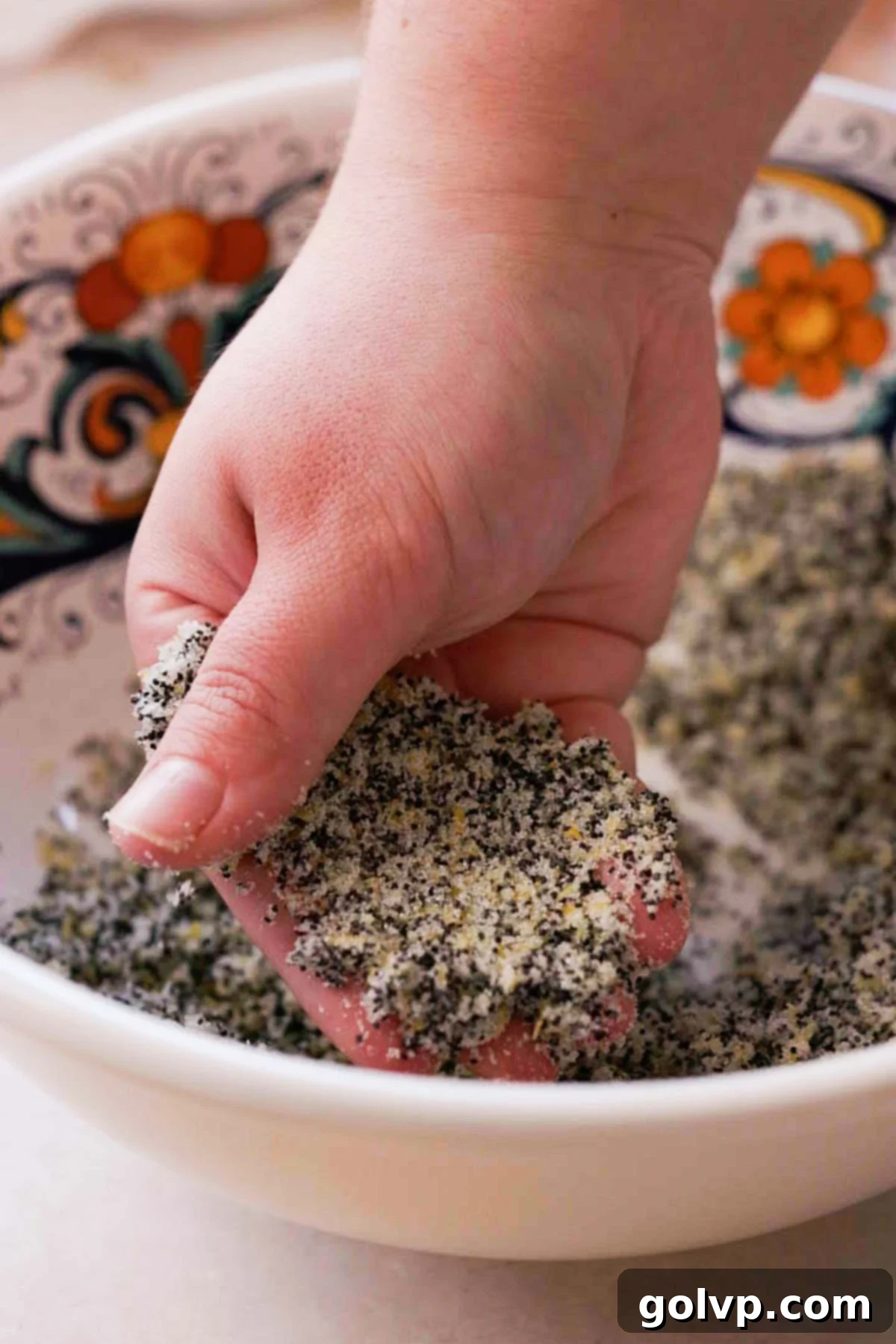 Rubbing fresh lemon zest, poppy seeds, and granulated sugar together with fingers to release fragrant oils