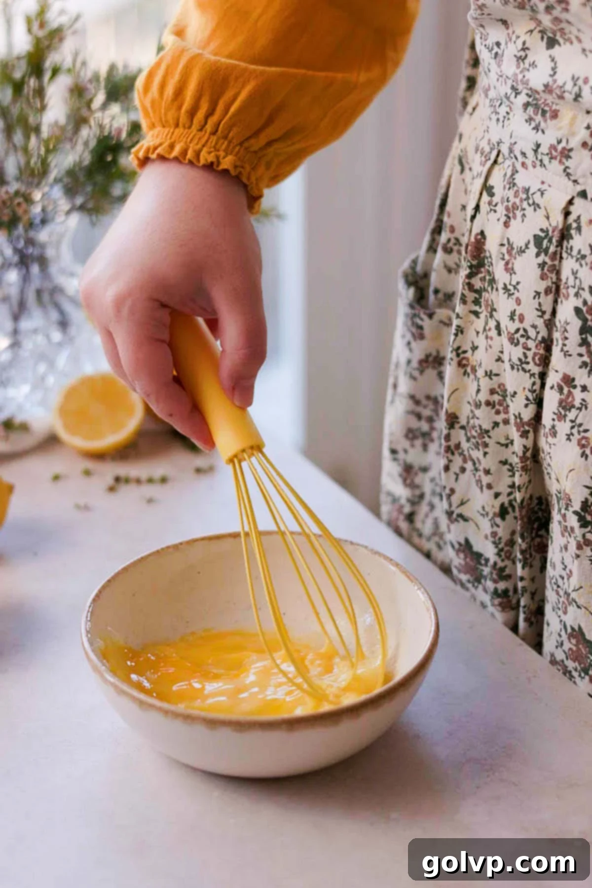 Whisking an egg wash mixture with a yellow whisk in a small bowl