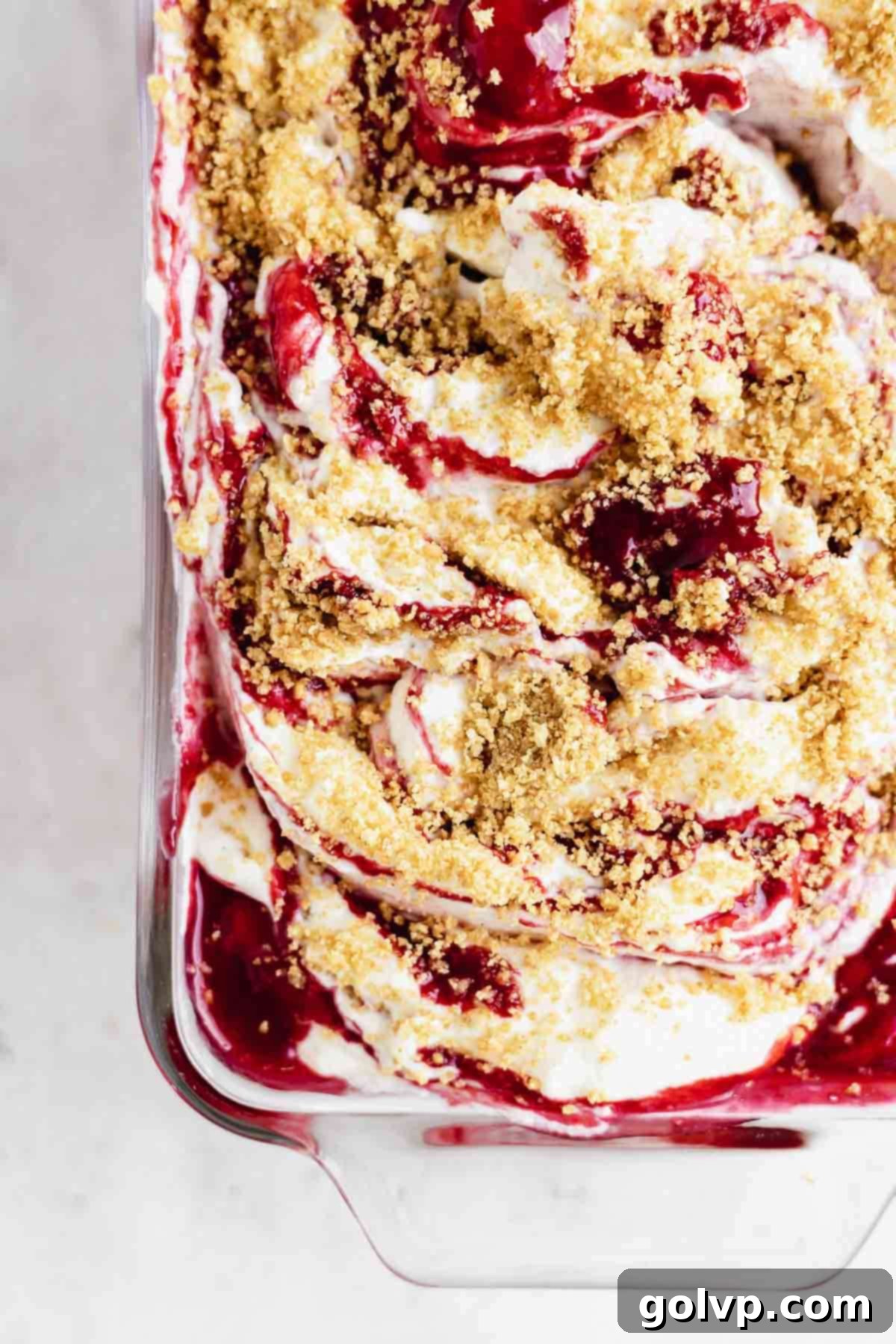 Closeup of raspberry cheesecake ice cream, showcasing vibrant pink swirls and graham cracker pieces